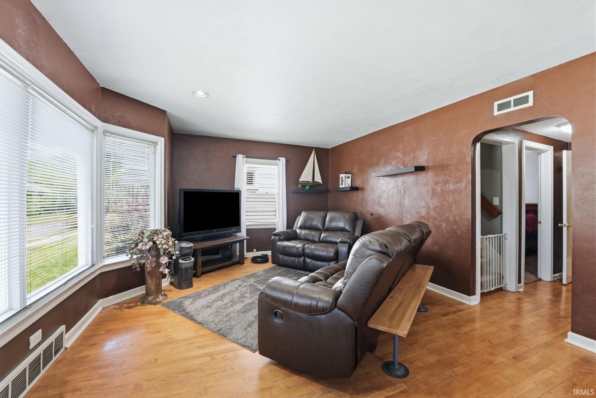 Living area featuring wood-finish flooring, a bay window with blinds, and recessed lighting