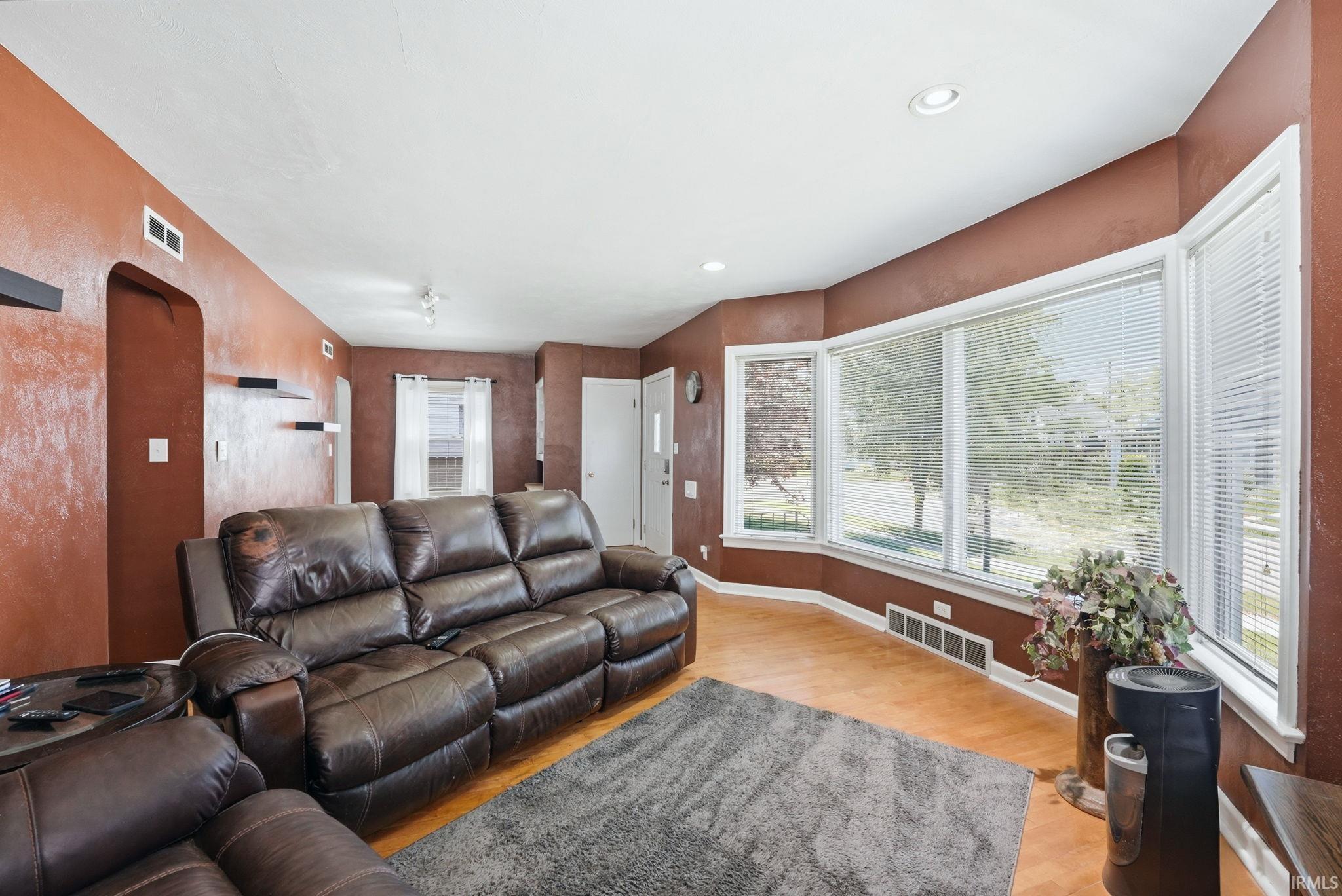 Living area featuring a prominent bay window with multiple panes, wood-finish flooring, and recessed ceiling lighting