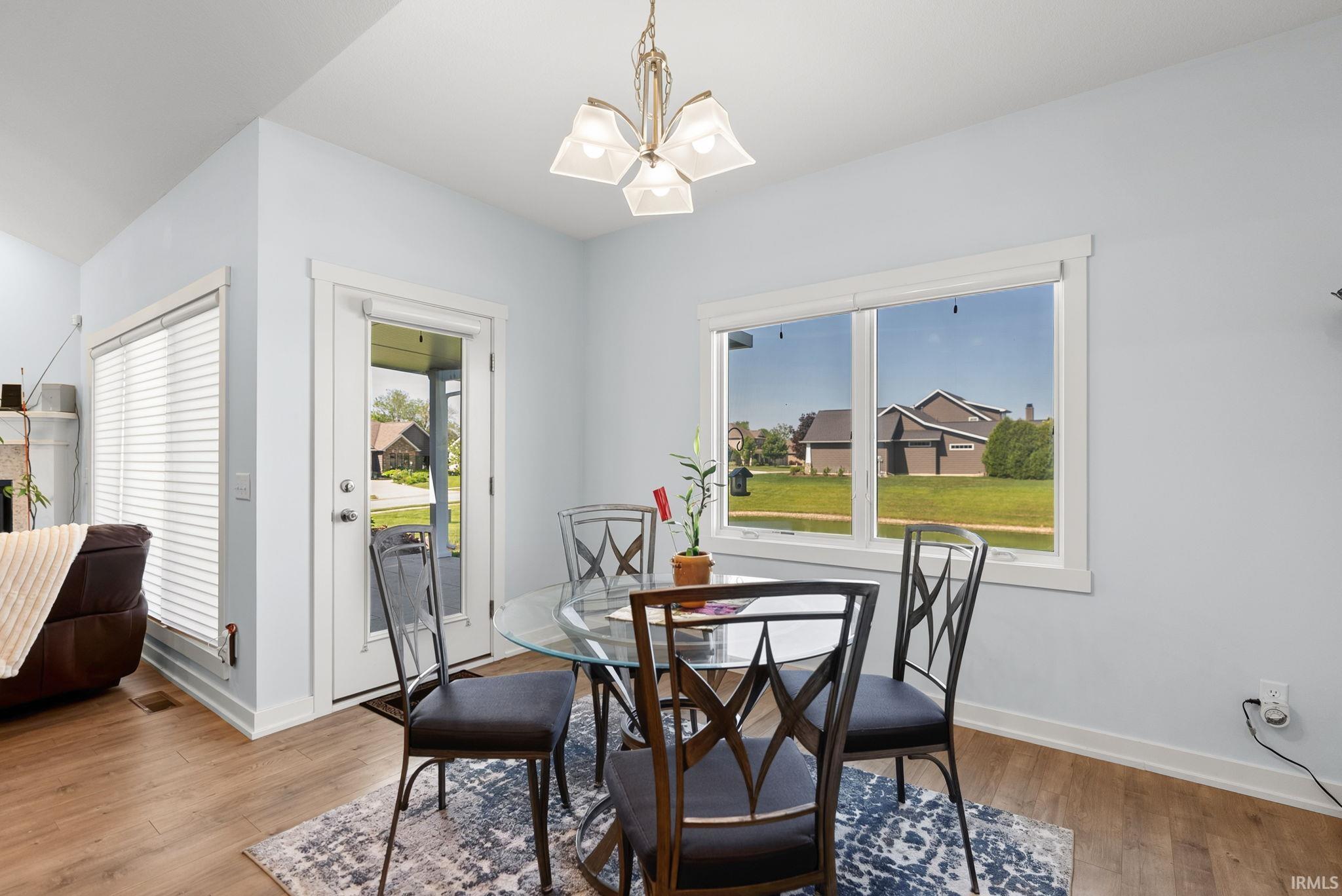 Dining area with wood-finish flooring, a contemporary chandelier, and light blue wall paint