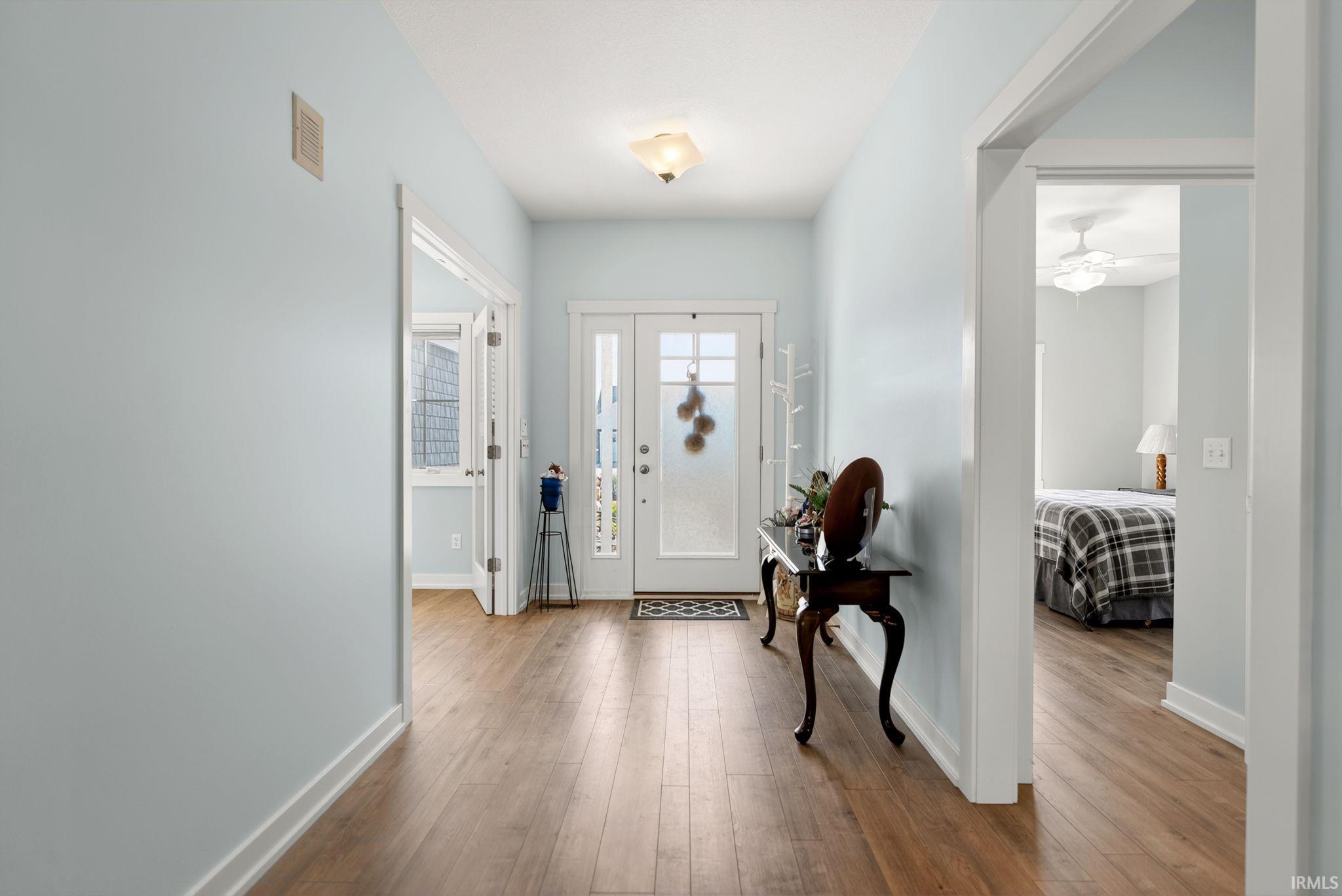 Entryway featuring wood-finish flooring, light blue wall paint, and white trim