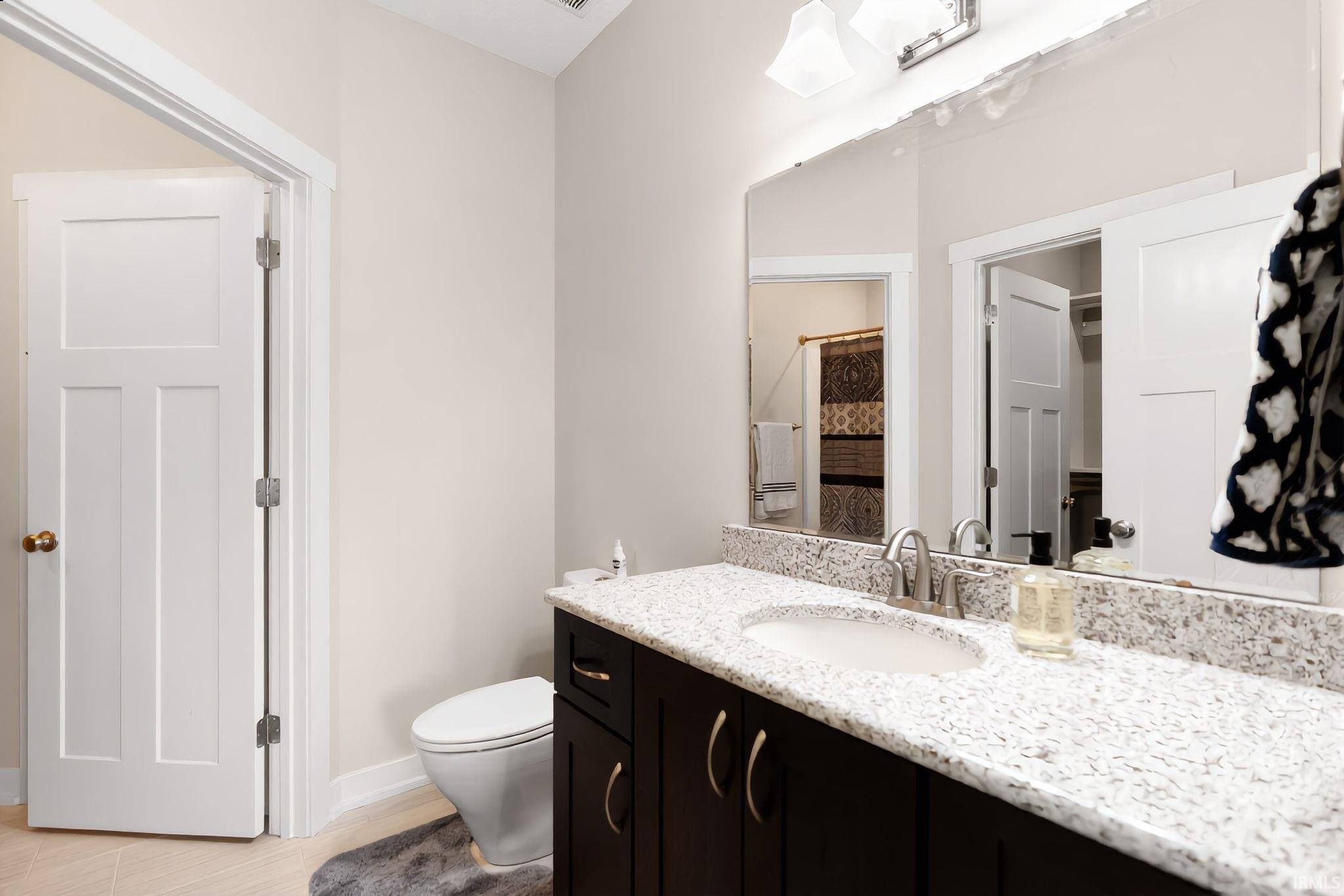 Bathroom featuring a dark wood-finish vanity with an undermount sink, speckled countertop, and brushed nickel hardware