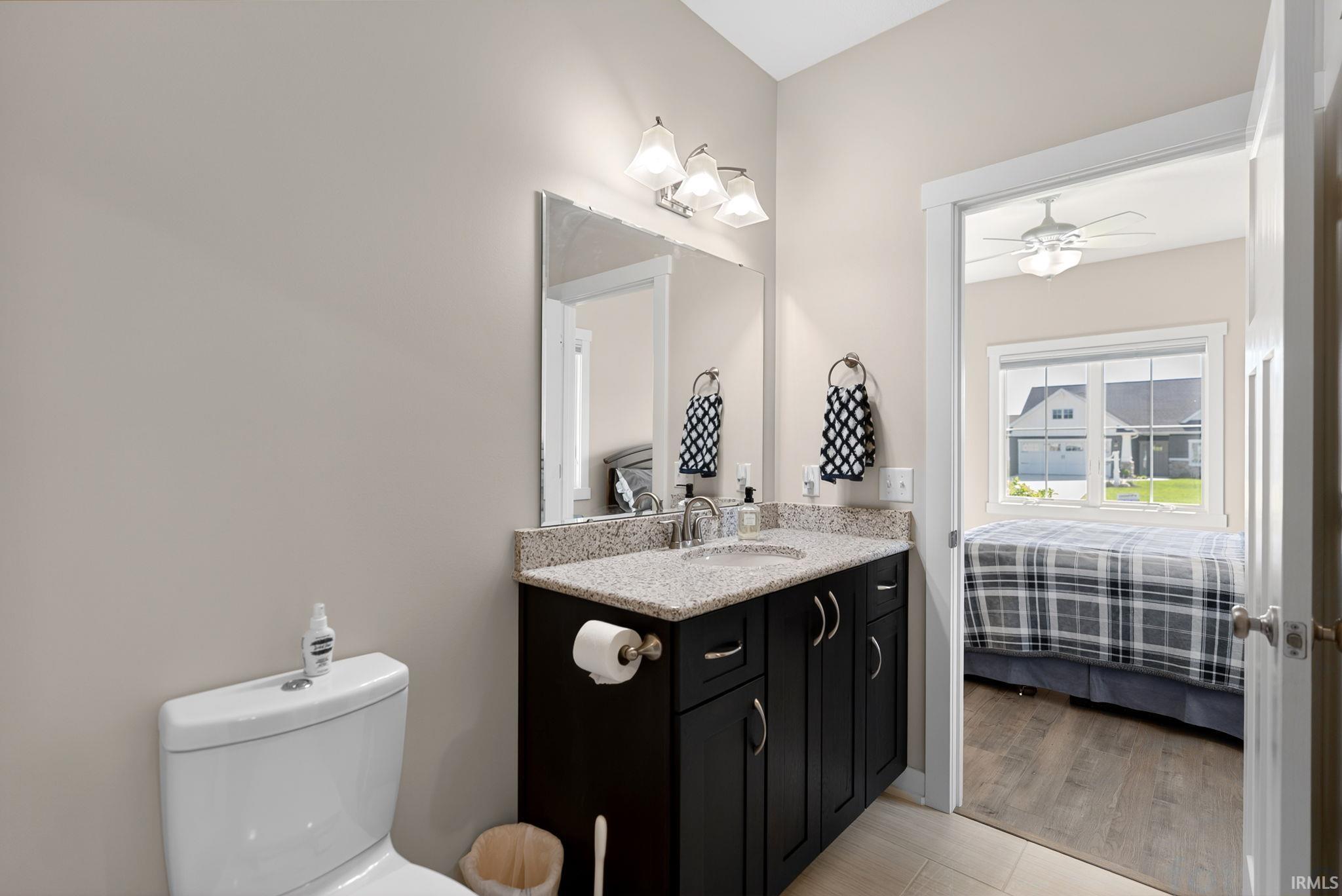 Bathroom vanity with dark wood cabinetry, a granite-finish countertop, and a chrome faucet