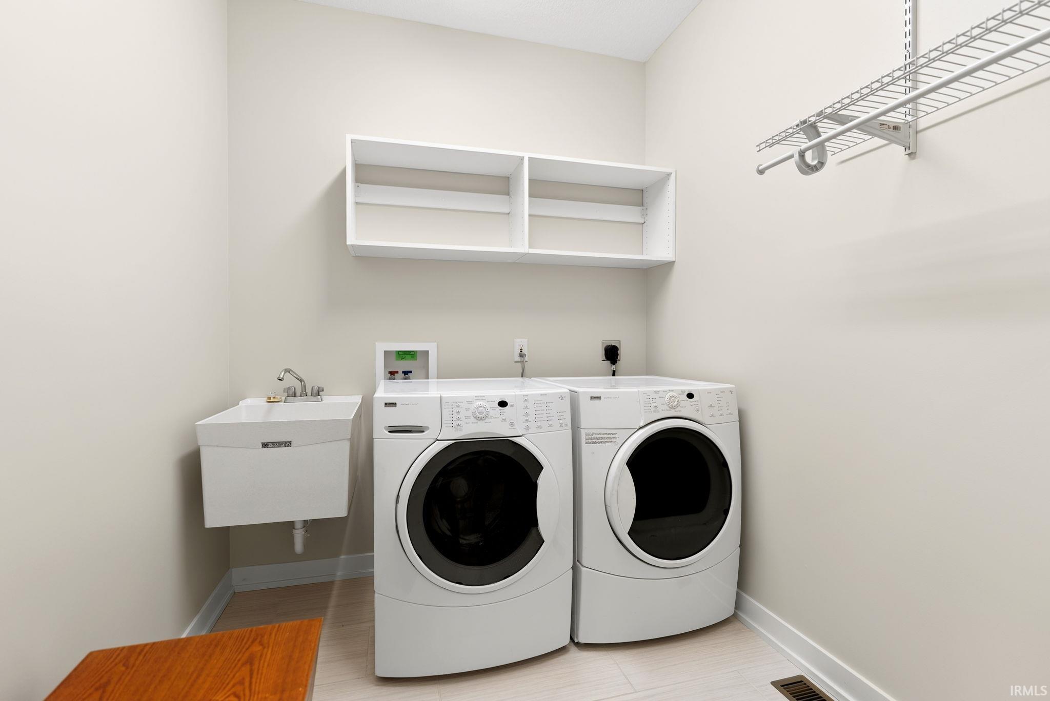 Dedicated laundry area featuring a utility sink, wall-mounted shelving, and wire rack storage