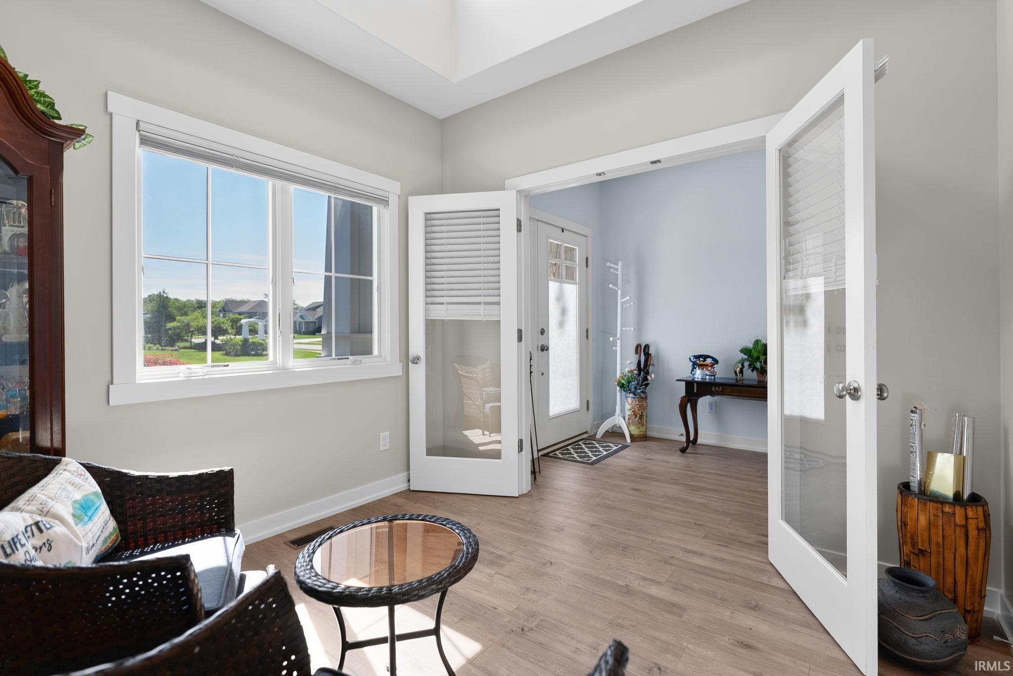 Bright interior space featuring wood-finish flooring, a large window with white trim, and a tray ceiling