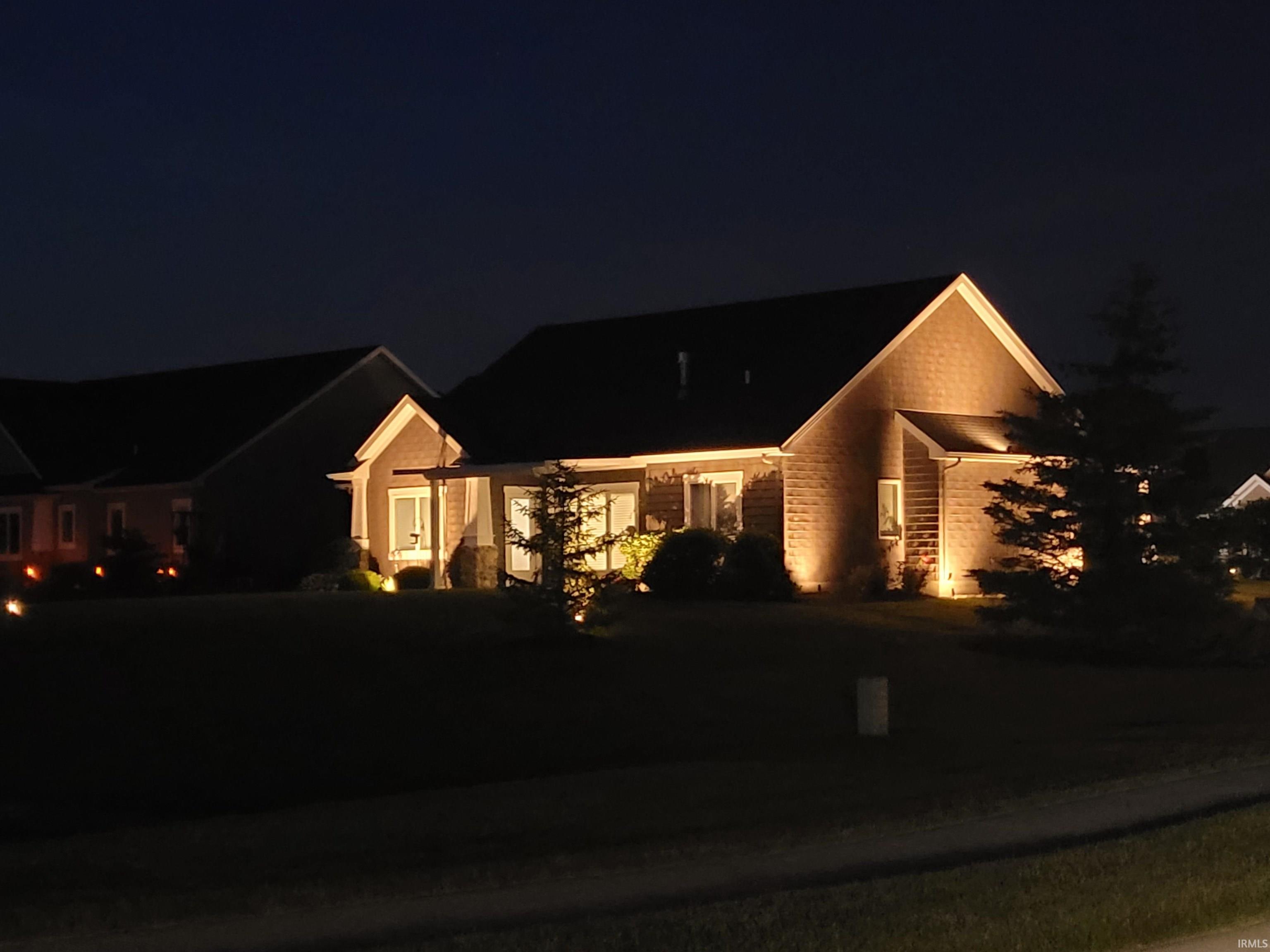 Exterior featuring stone facade, gabled rooflines, covered entry, and landscape lighting
