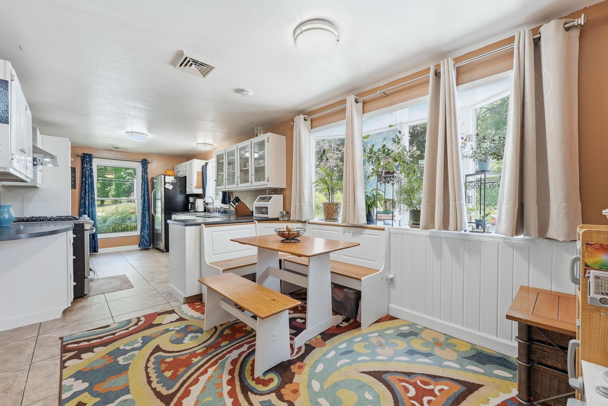 Eat-in kitchen featuring white cabinetry, an integrated breakfast nook, tile flooring, and multiple windows