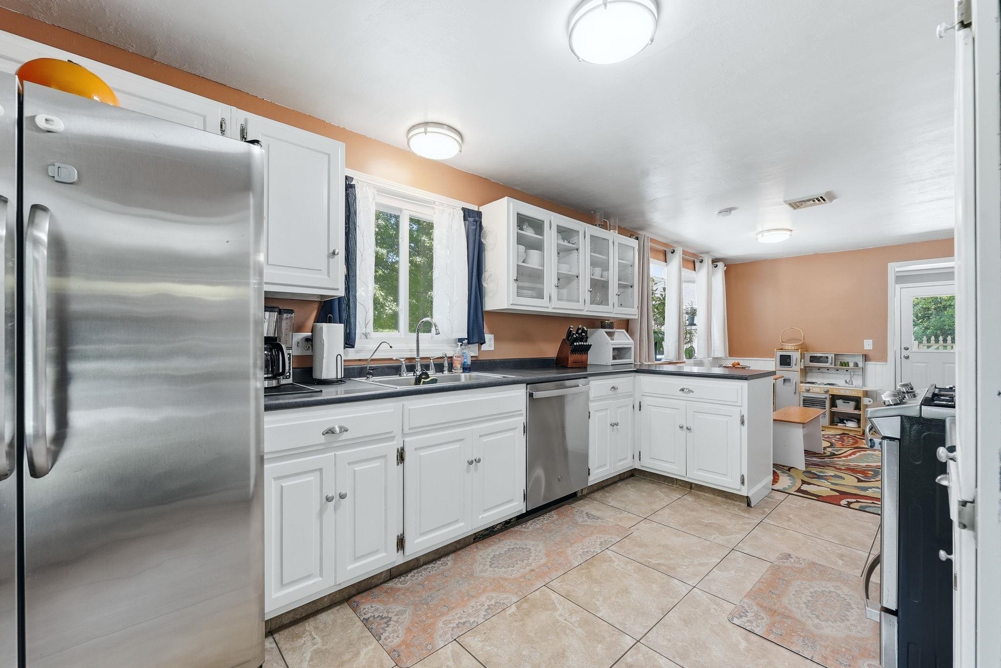 Kitchen featuring white cabinetry, dark countertops, tiled flooring, and stainless steel appliances