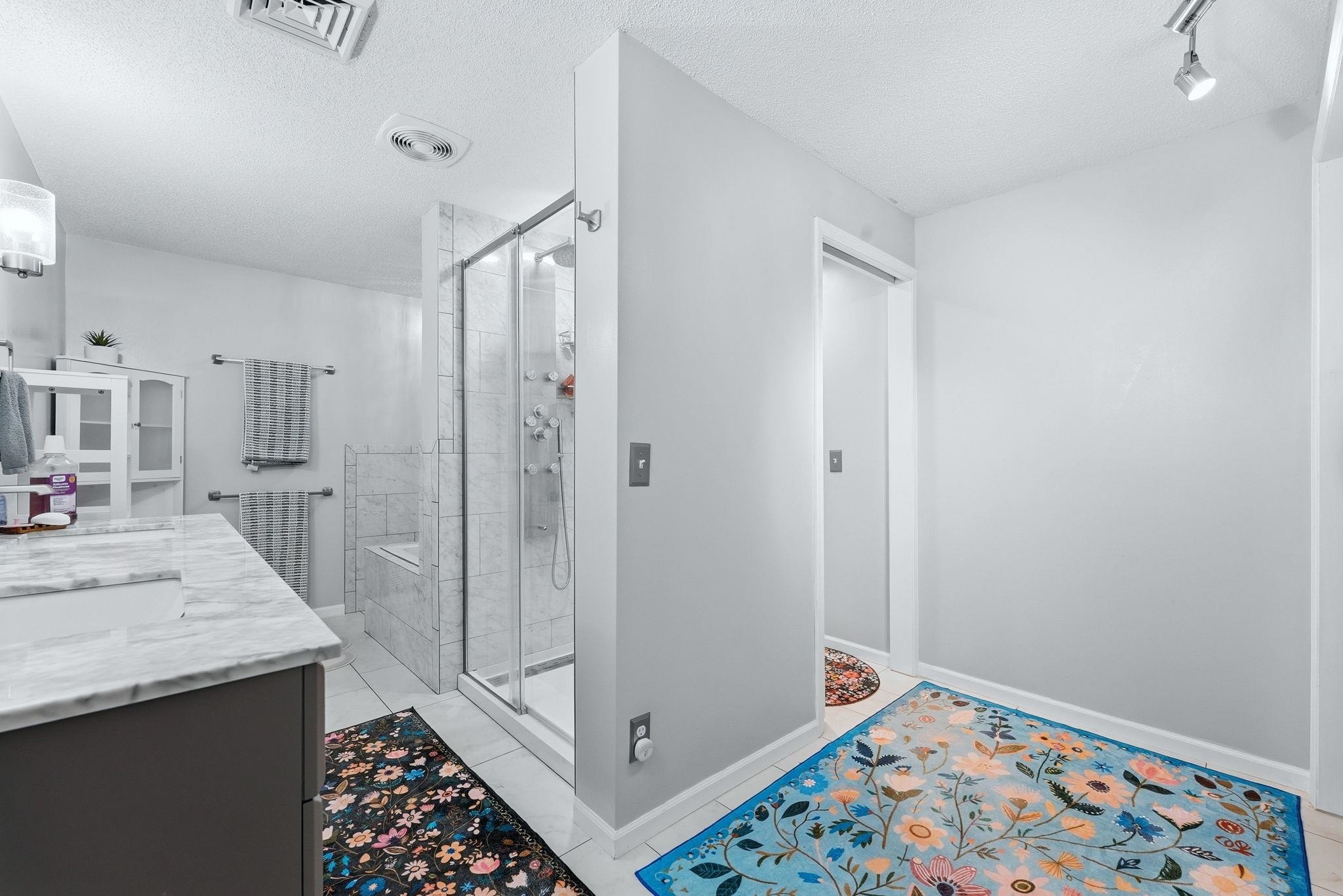 Bathroom featuring a glass-enclosed shower with tile surround, a built-in shower bench, and a dual shower head system