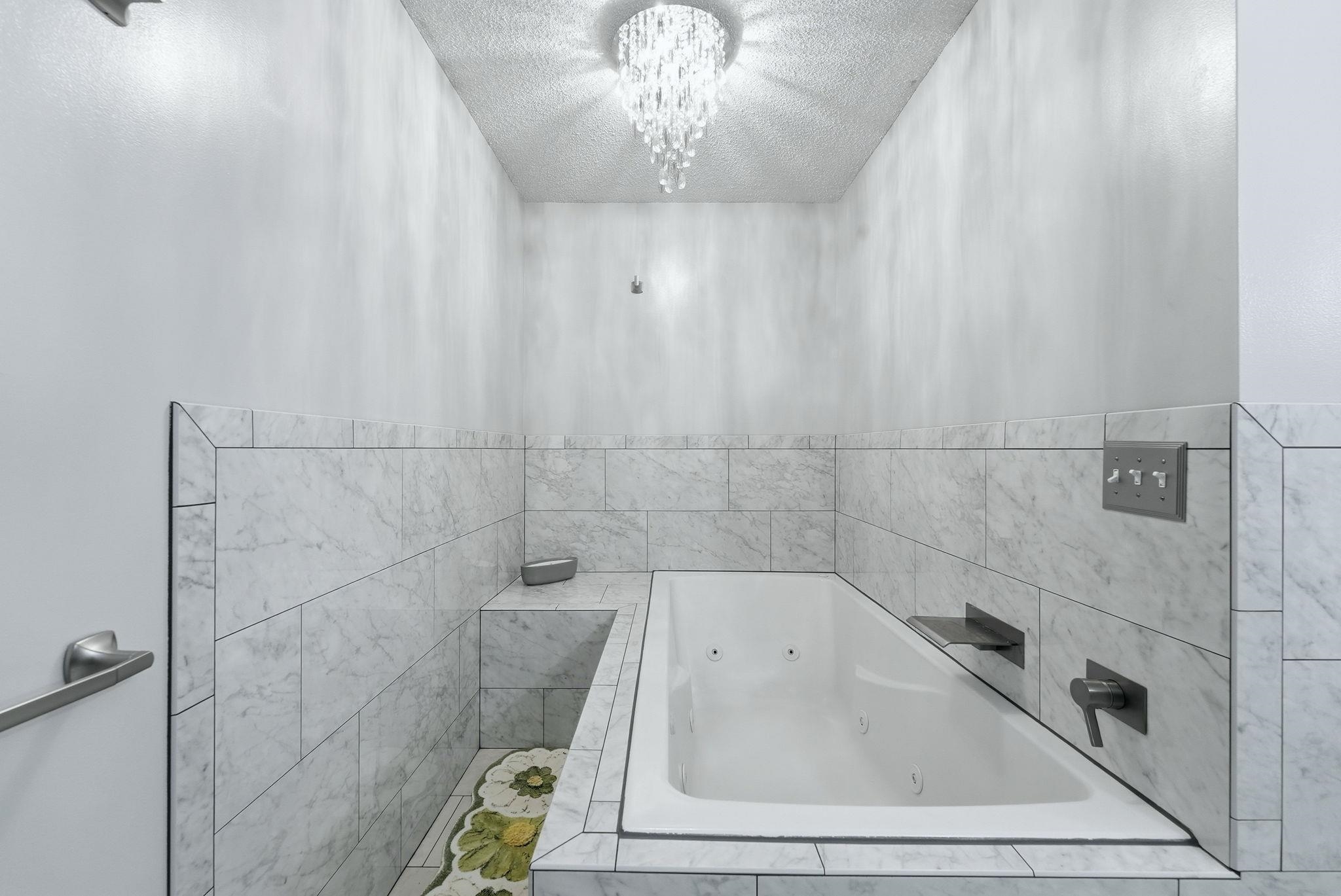 Soaking tub with integrated jets, surrounded by marble-style tile
