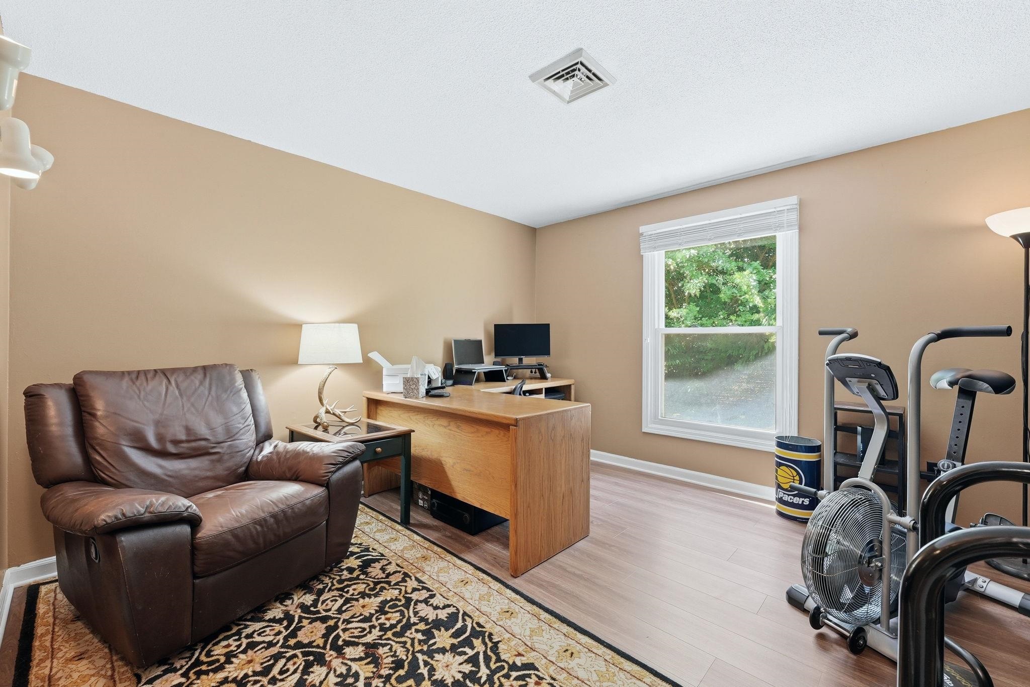 Versatile room featuring neutral wall tones, wood-finish flooring, and a large window providing ample natural light