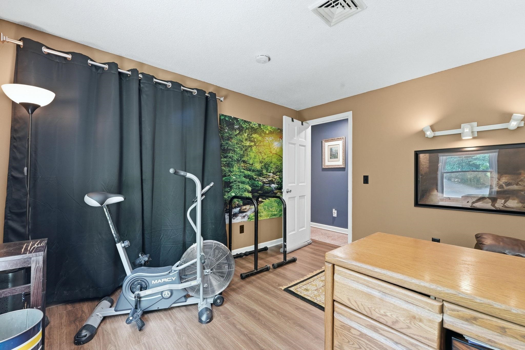 Room featuring wood-finish flooring, warm-toned wall paint, and a white ceiling with a central vent