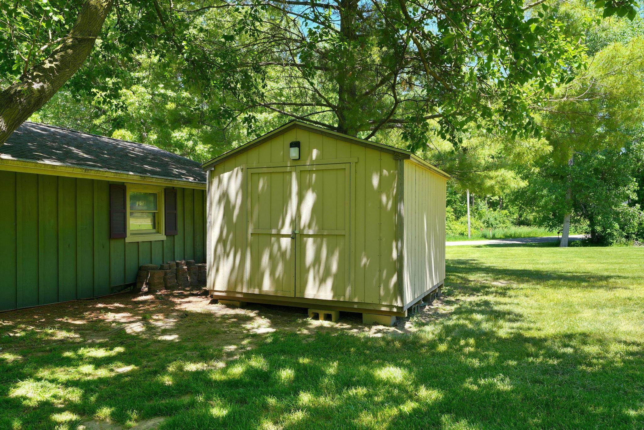 Freestanding shed with double entry doors and exterior lighting, set on a grassy lawn