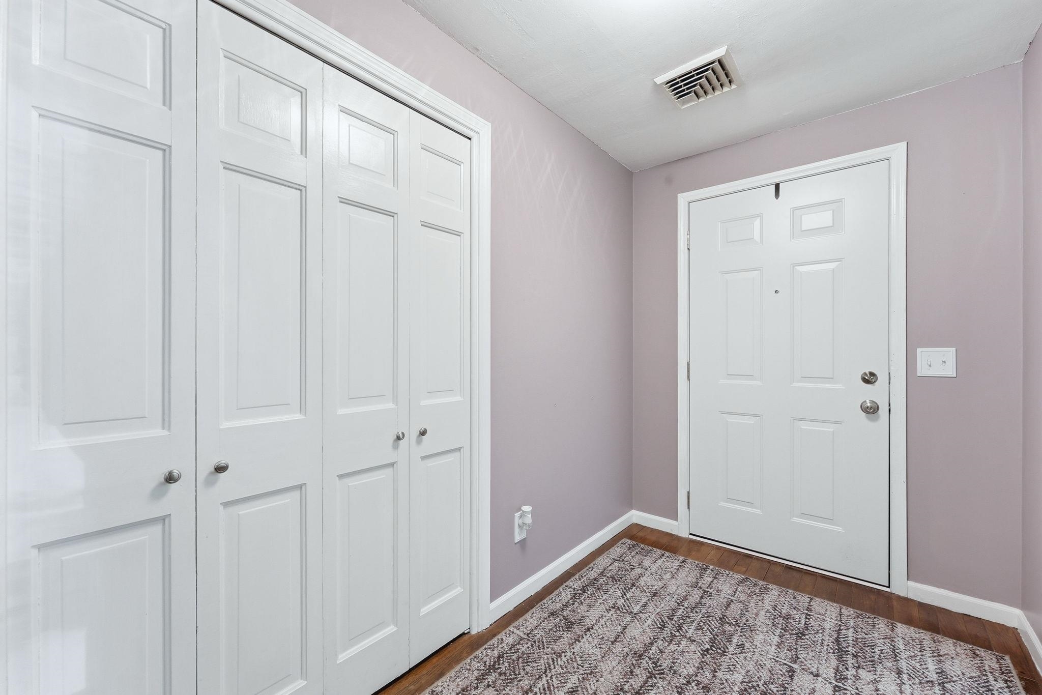 Recessed lighting illuminating the entry with wood-finish flooring