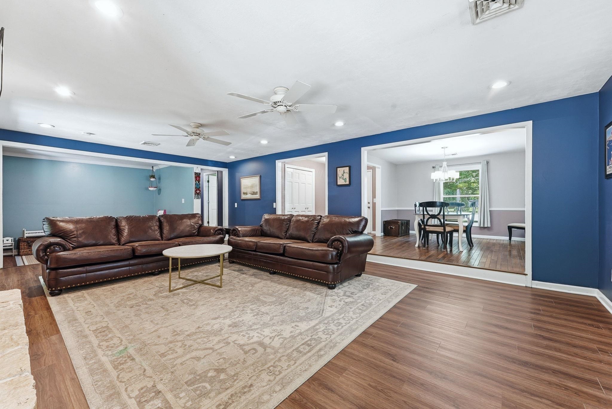 Spacious living area featuring wood-finish flooring, recessed lighting, and ceiling fans