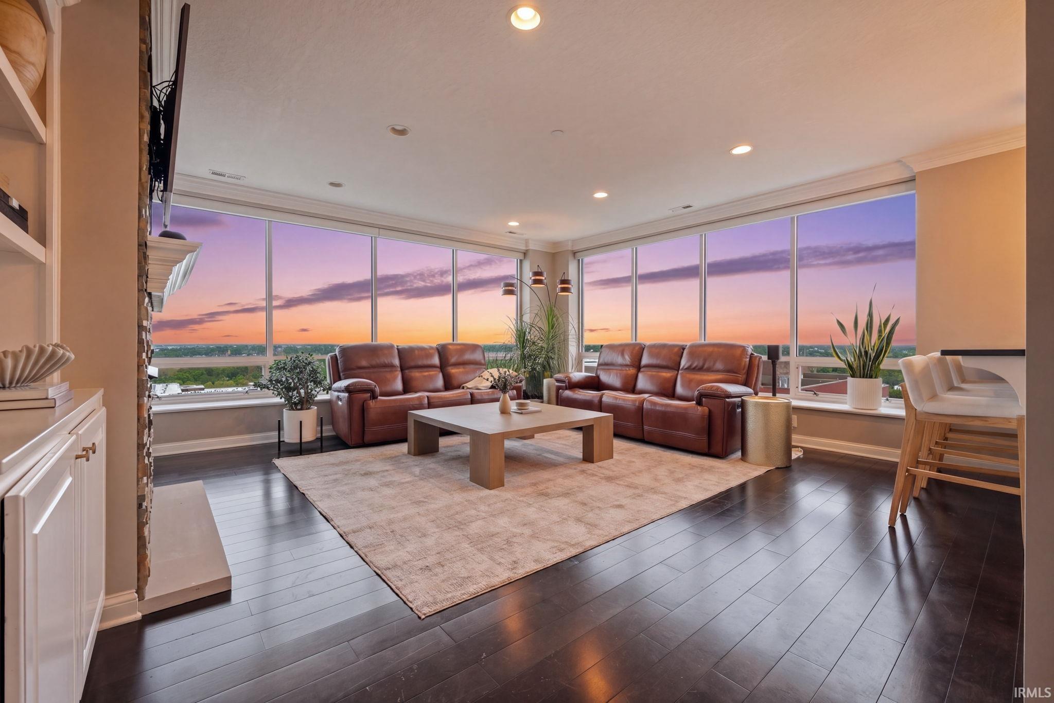 Expansive living space featuring dark wood-finish flooring, a contemporary built-in shelving unit, and recessed lighting
