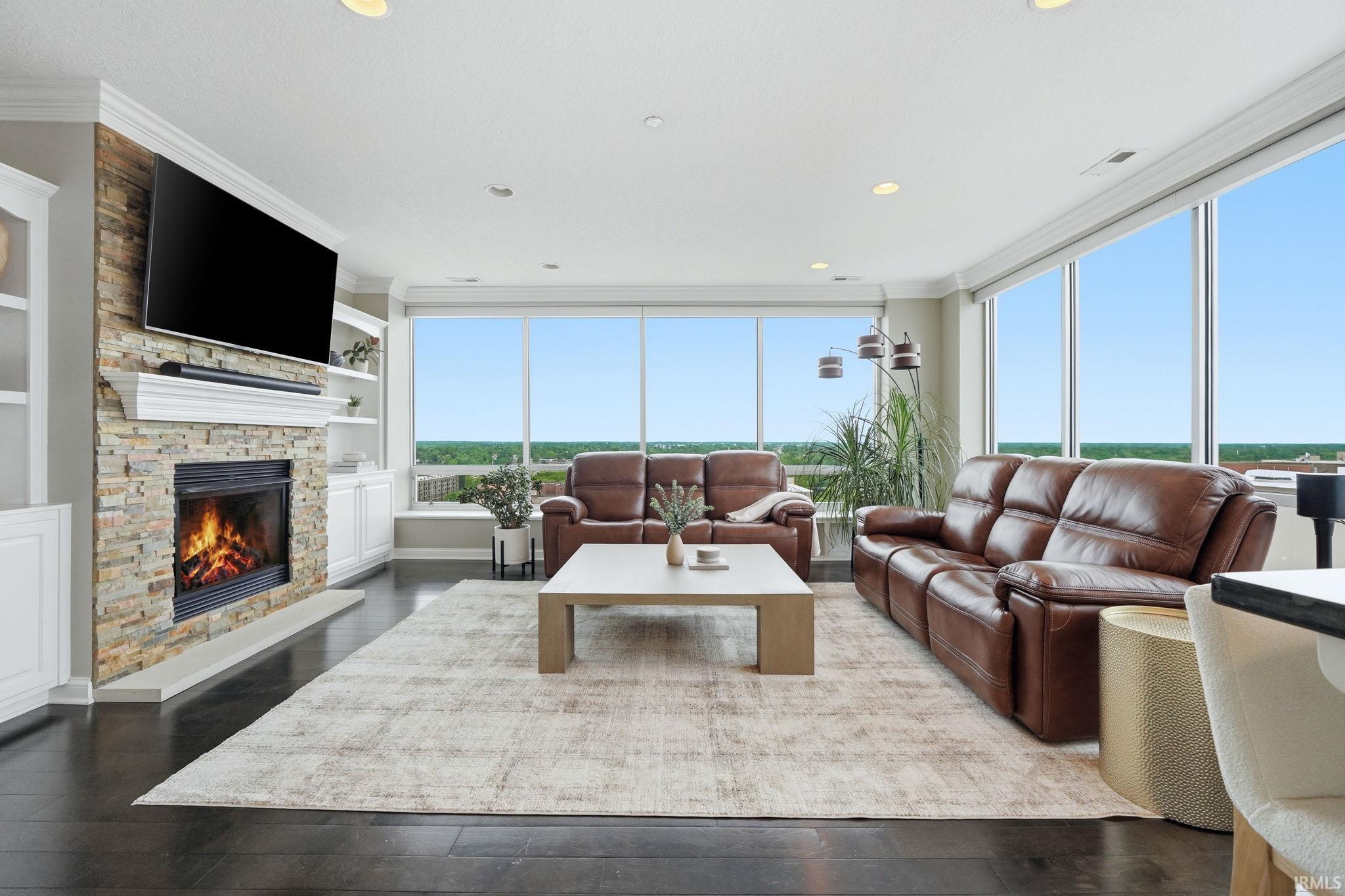 Living area featuring dark wood-finish flooring and a stacked stone fireplace with a white mantel