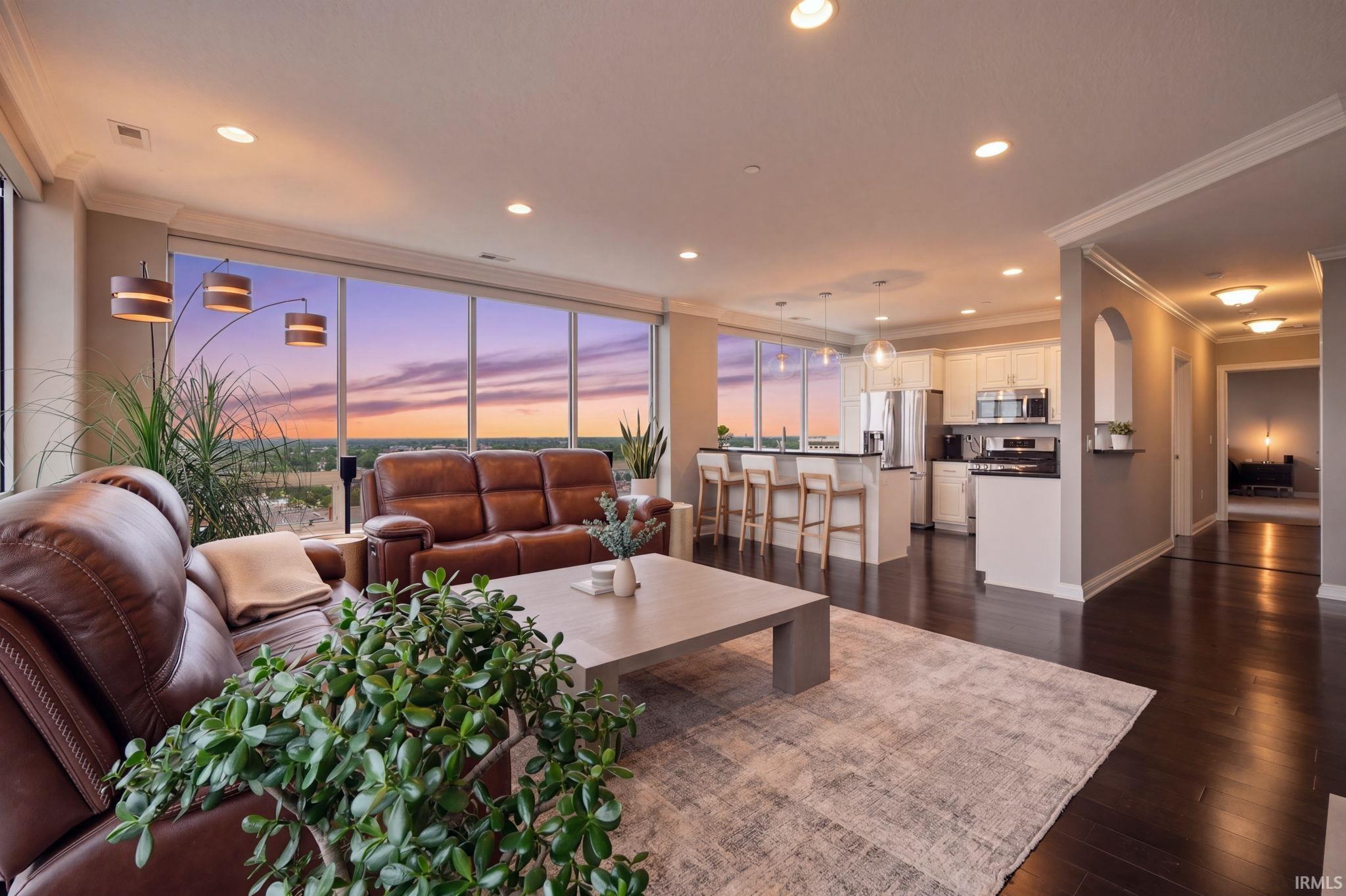 Open-concept living area with expansive floor-to-ceiling windows, dark wood-finish flooring, recessed lighting, and crown molding