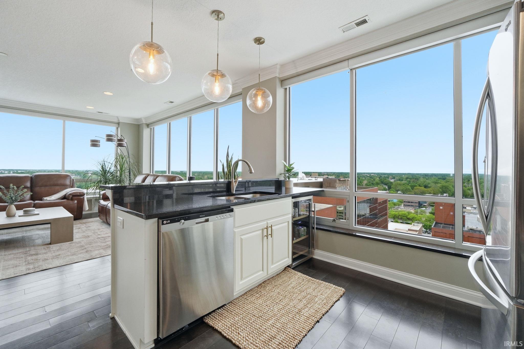 Kitchen island with black countertop and stainless steel appliances, open to a living area with dark wood-finish flooring