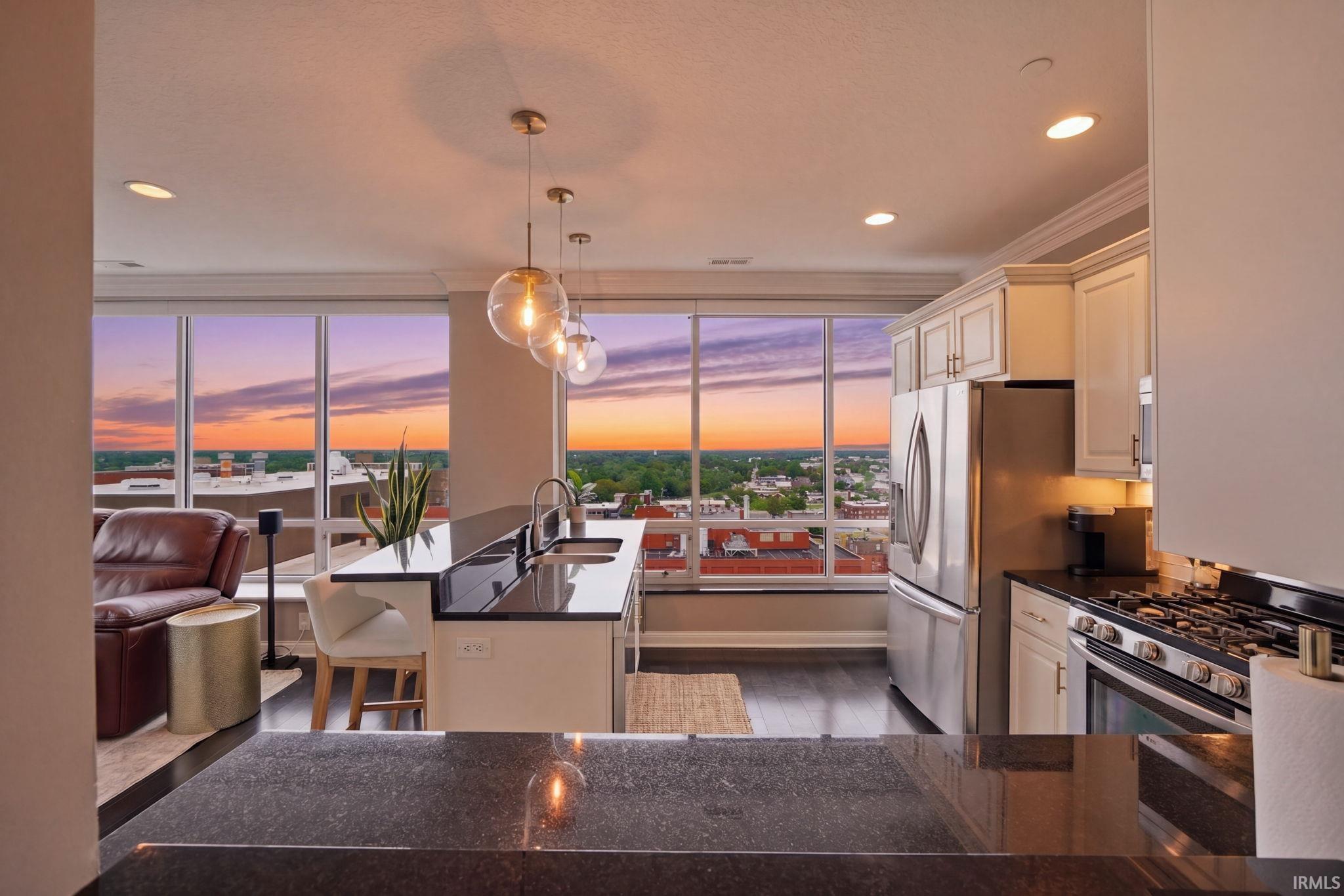 Open-concept kitchen featuring dark countertops, white cabinetry, and stainless steel appliances
