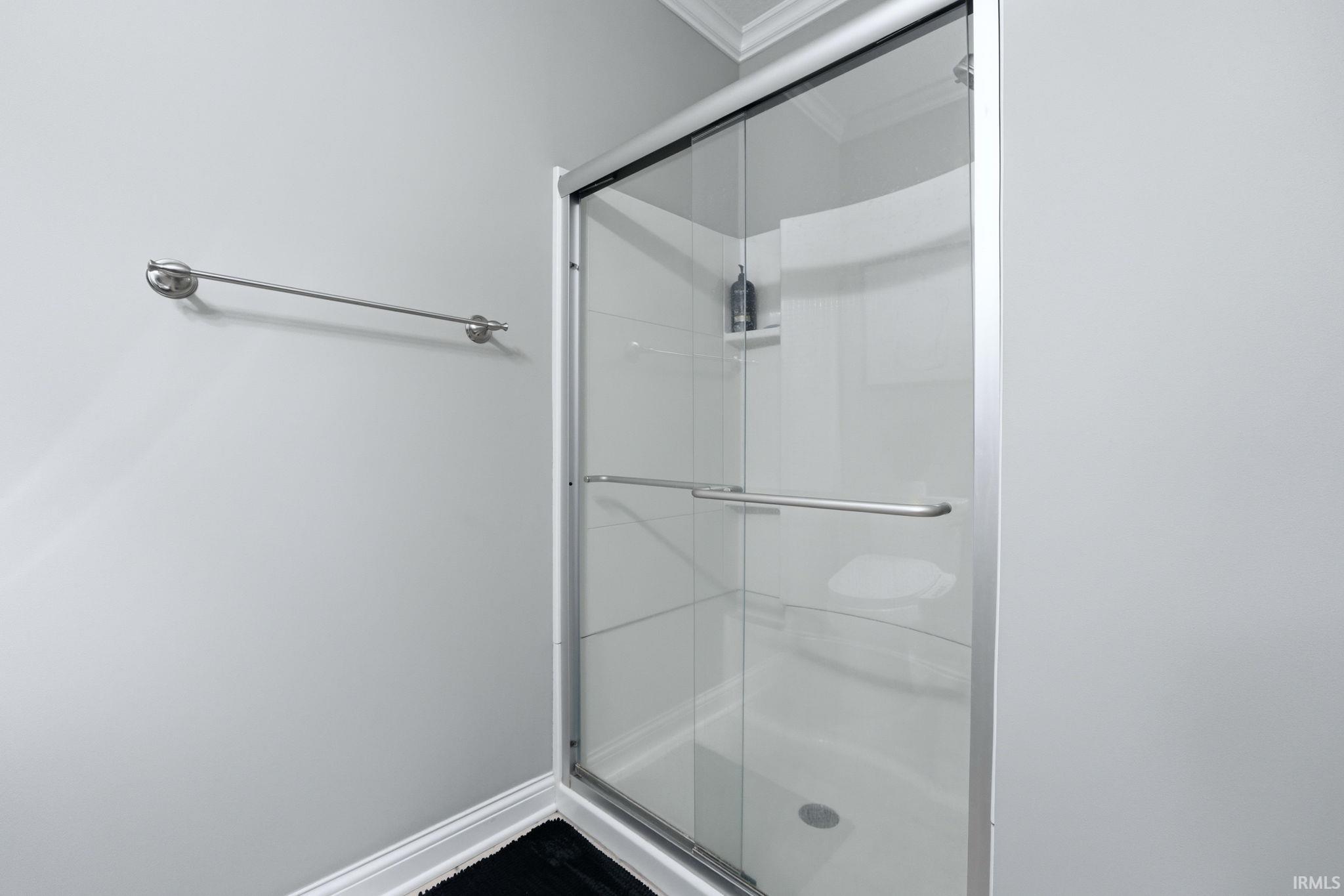 Enclosed shower featuring clear glass doors with chrome framing and hardware, a built-in shower caddy, and a white shower base