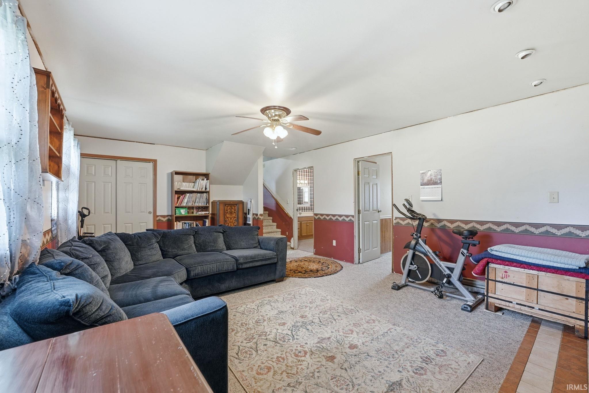 Spacious living area featuring light-colored carpeting, a ceiling fan with integrated lighting, and recessed ceiling lights