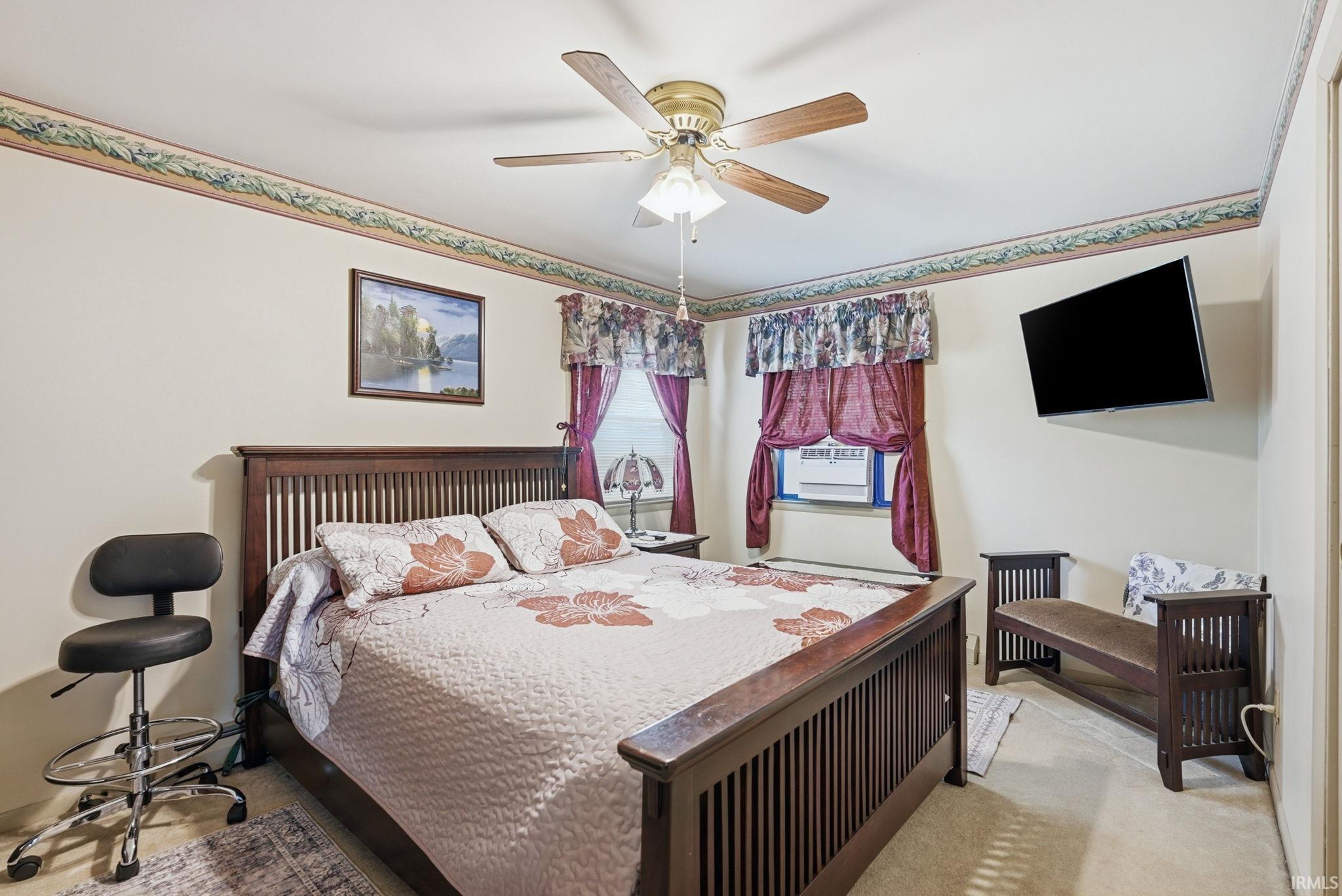 Carpeted room featuring a ceiling fan with integrated lighting, light-toned wall paint, and a decorative border