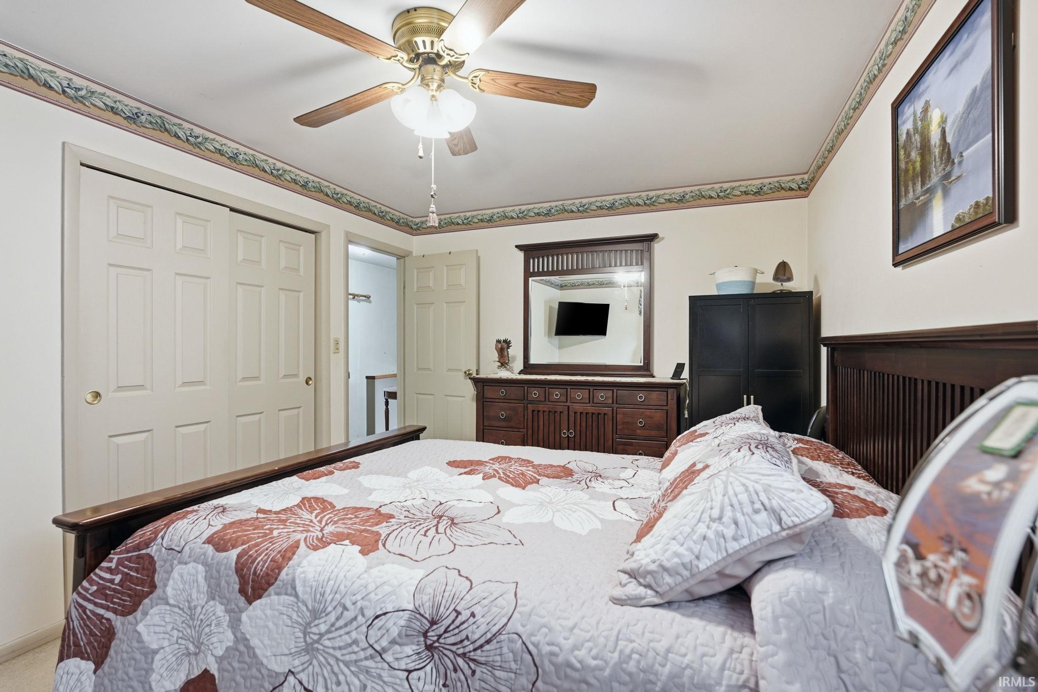 Bedroom featuring a ceiling fan with integrated lighting, wall-to-wall carpeting, and a closet with bifold doors