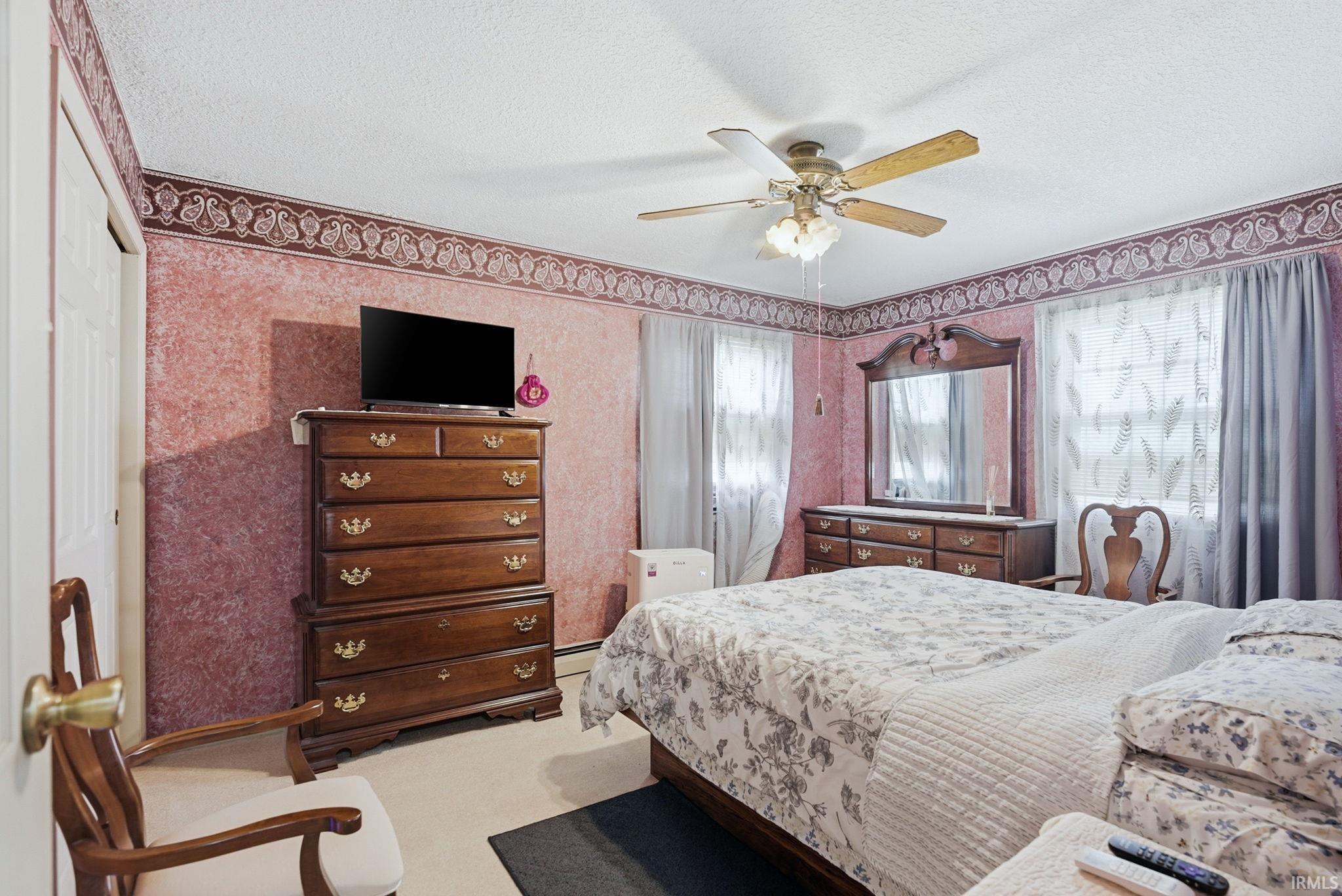 Spacious room featuring textured wall covering, a decorative ceiling border, and a ceiling fan with light fixture