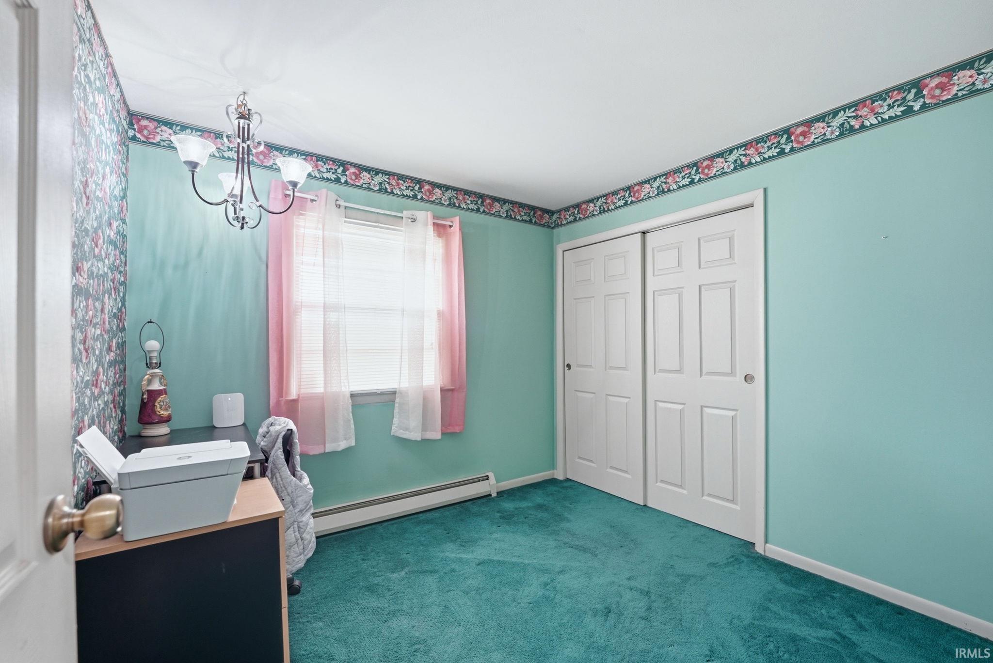 Room featuring teal walls, a white ceiling with decorative floral border, and green carpet flooring