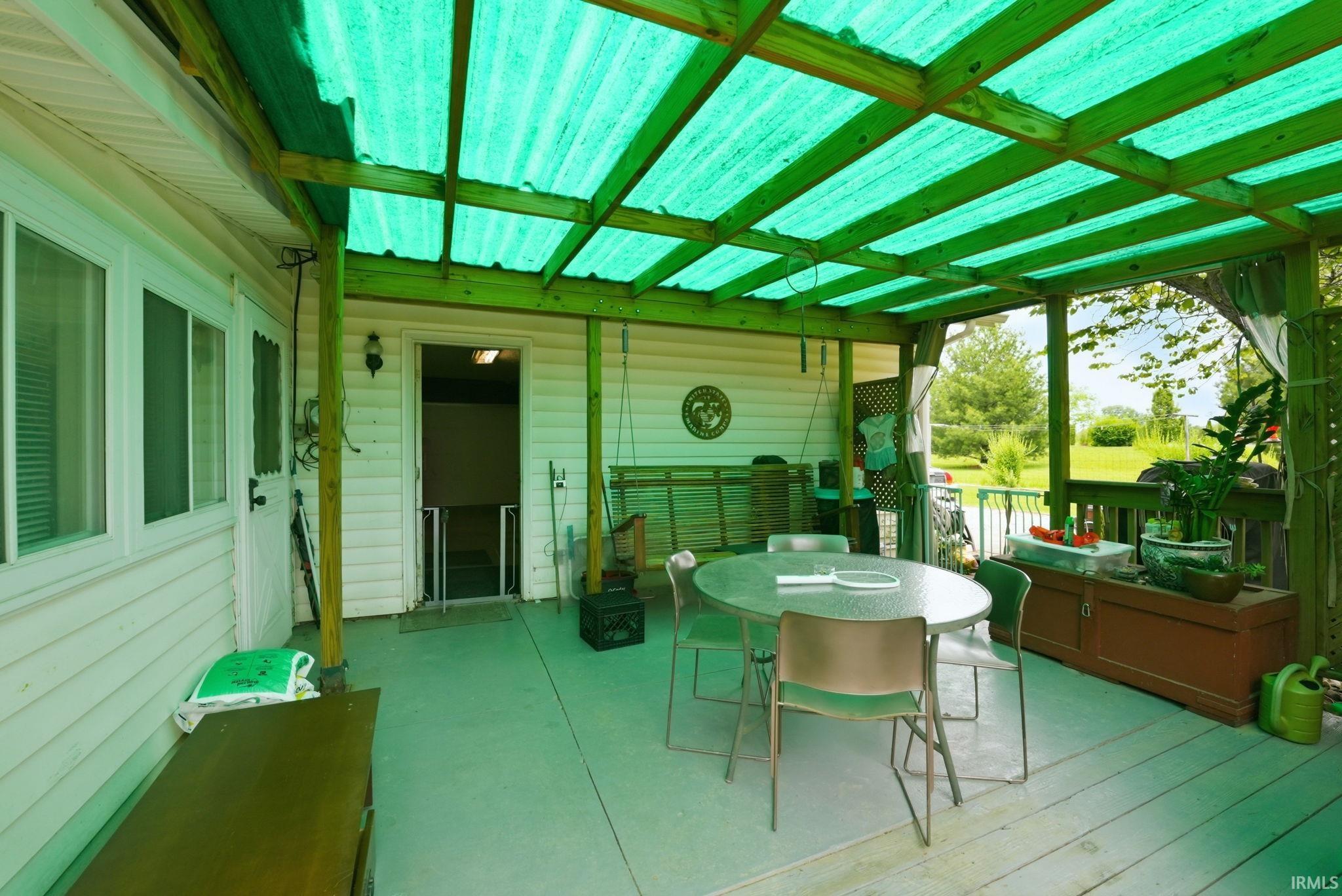 Covered outdoor patio area featuring a green corrugated roof and wood beam supports