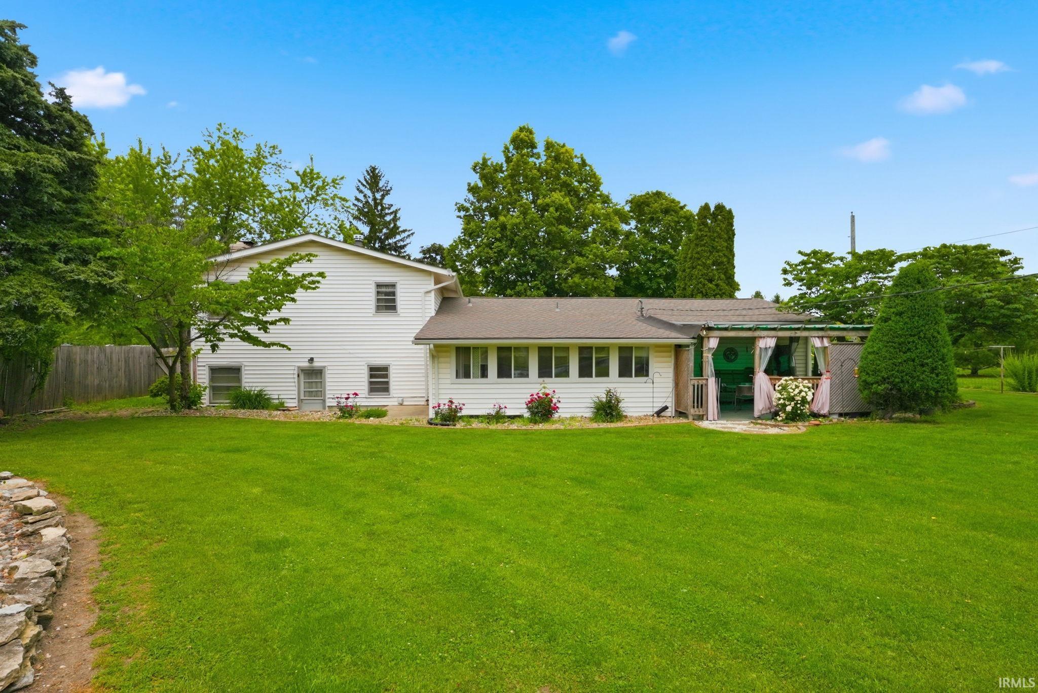 Expansive green lawn with a white vinyl-sided residence