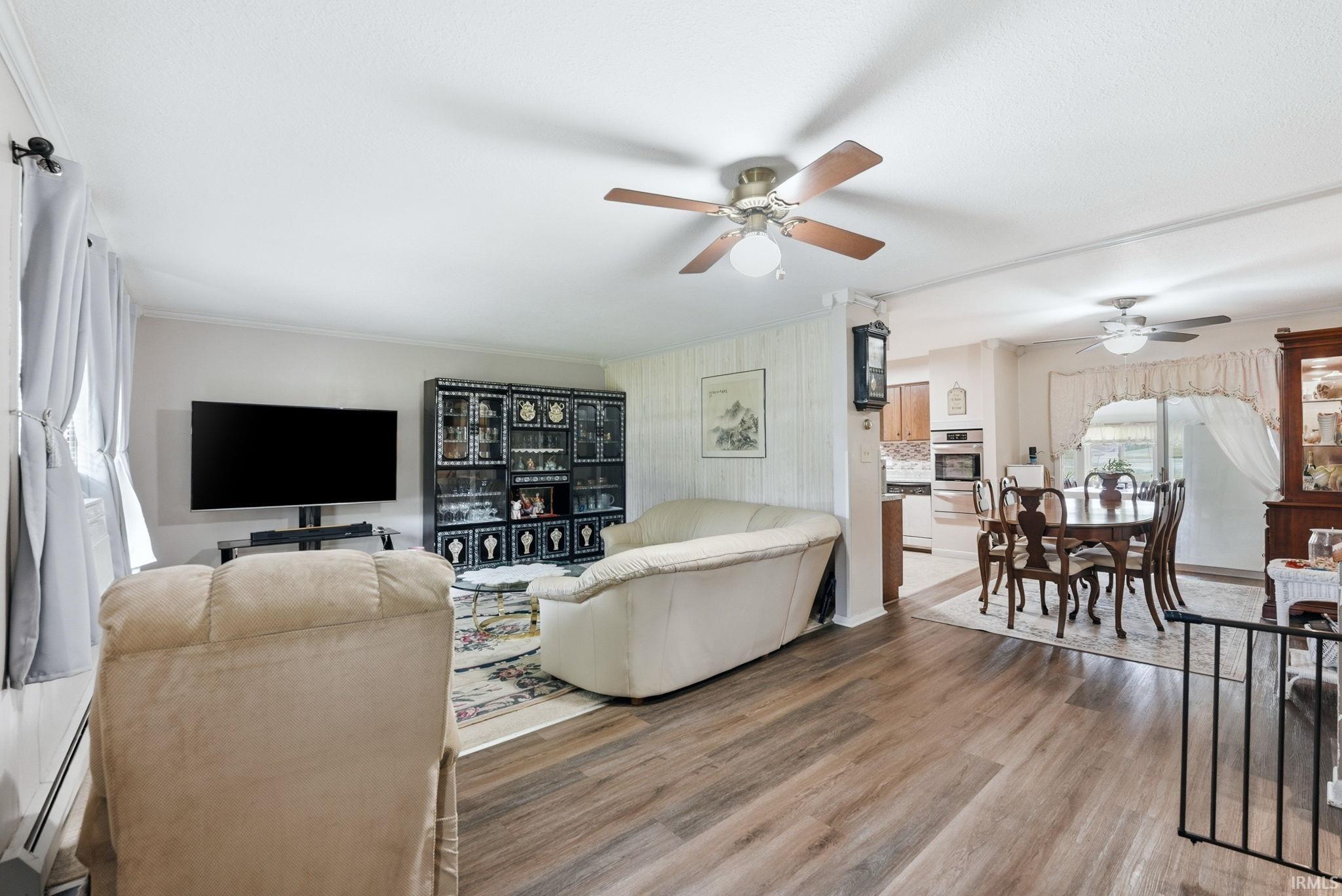 Spacious open-concept interior featuring wood-finish flooring, two ceiling fans with integrated lighting, and a dining area with a sliding glass door