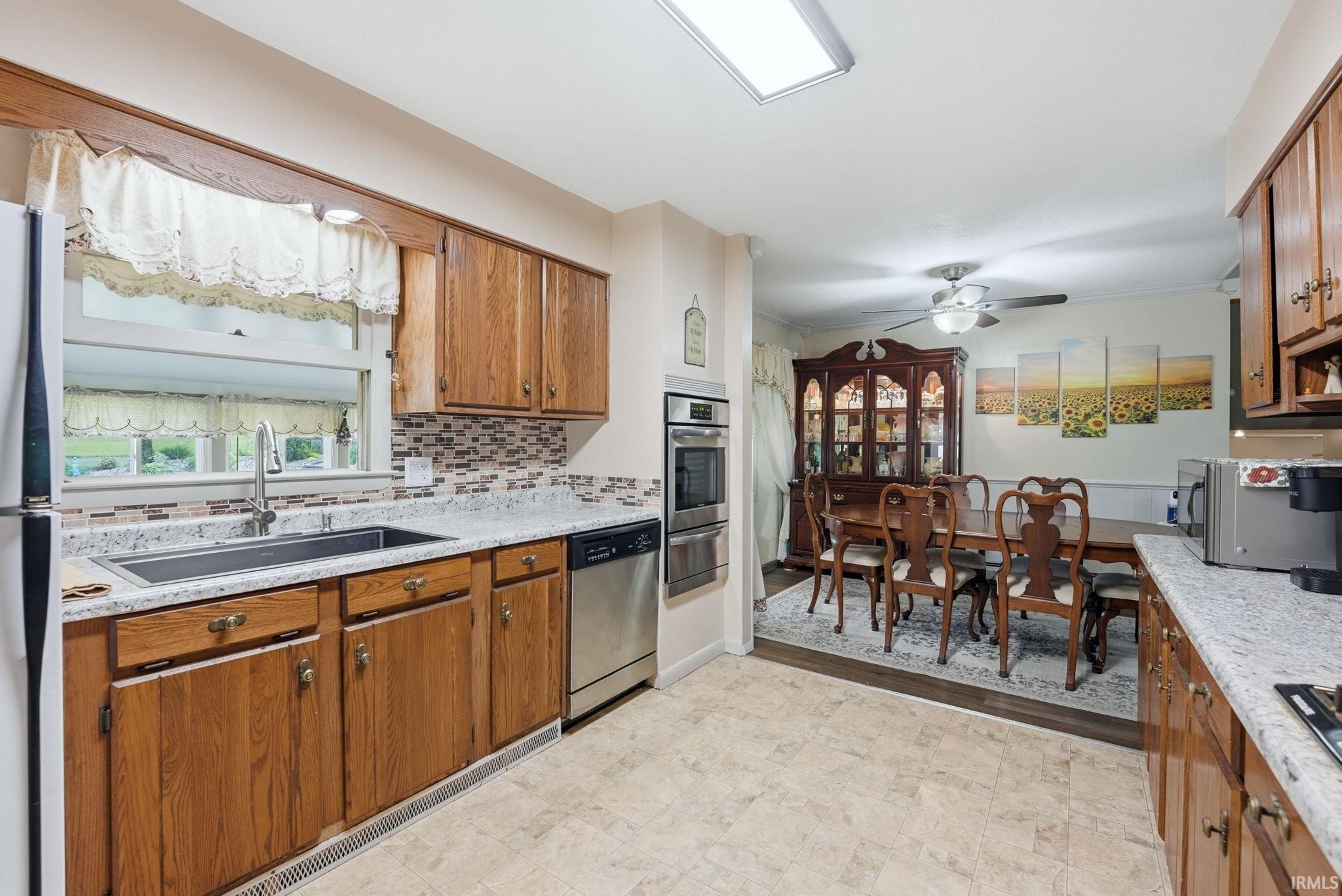 Kitchen featuring wood cabinetry, light-toned countertops, a mosaic tile backsplash, and stainless steel appliances