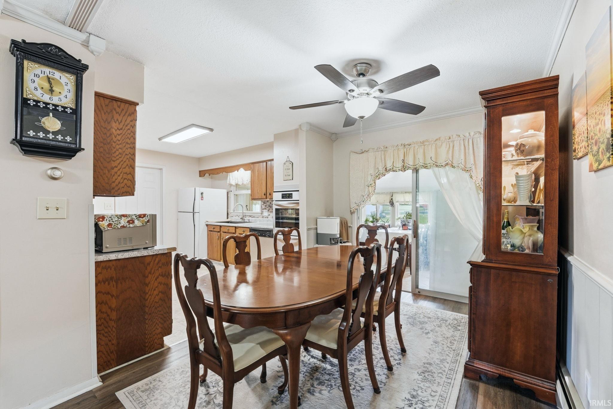 Dining area featuring wood-finish flooring, a ceiling fan with integrated lighting, and a sliding glass door providing natural light