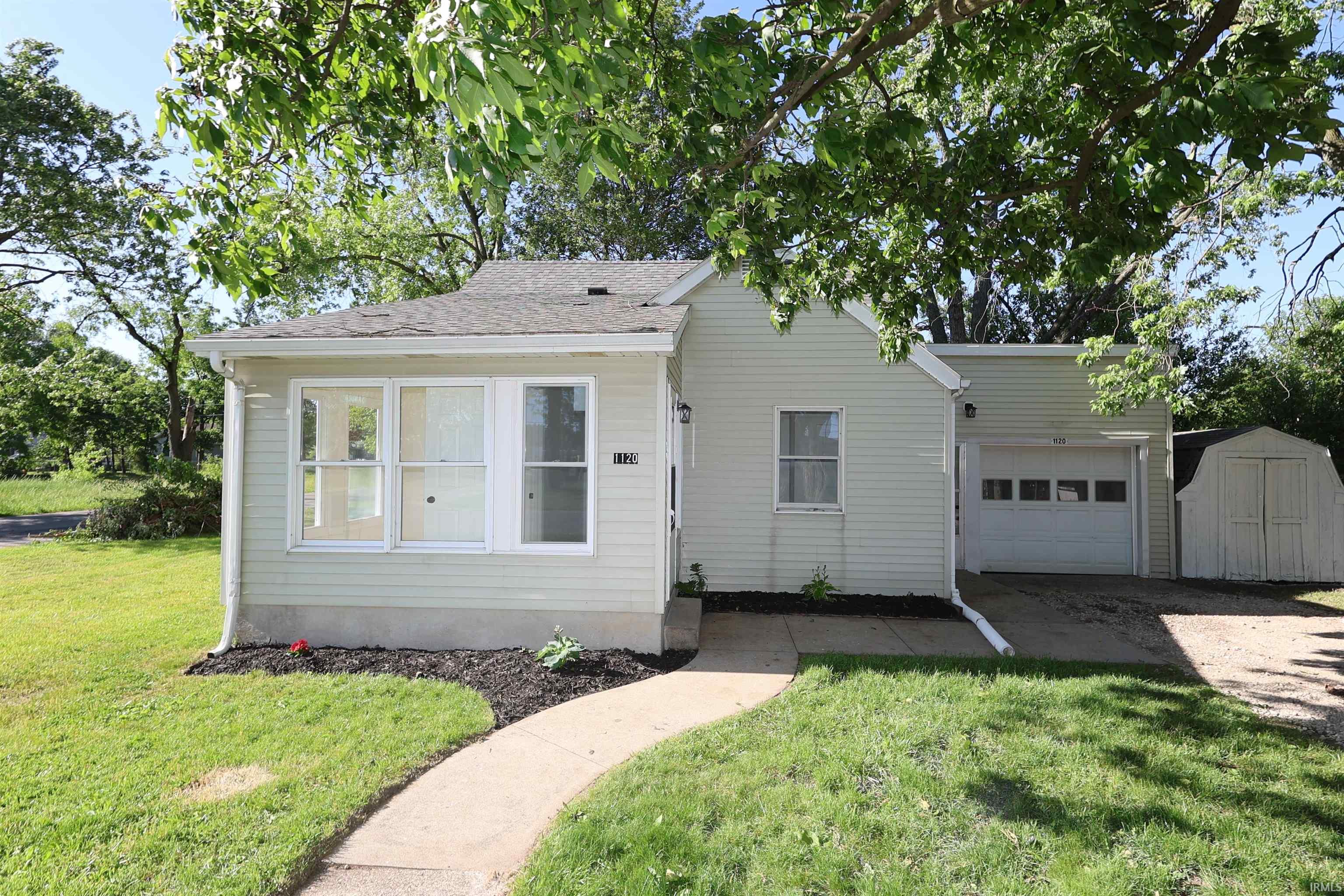 Light-colored siding exterior with a single-car garage and a paved driveway