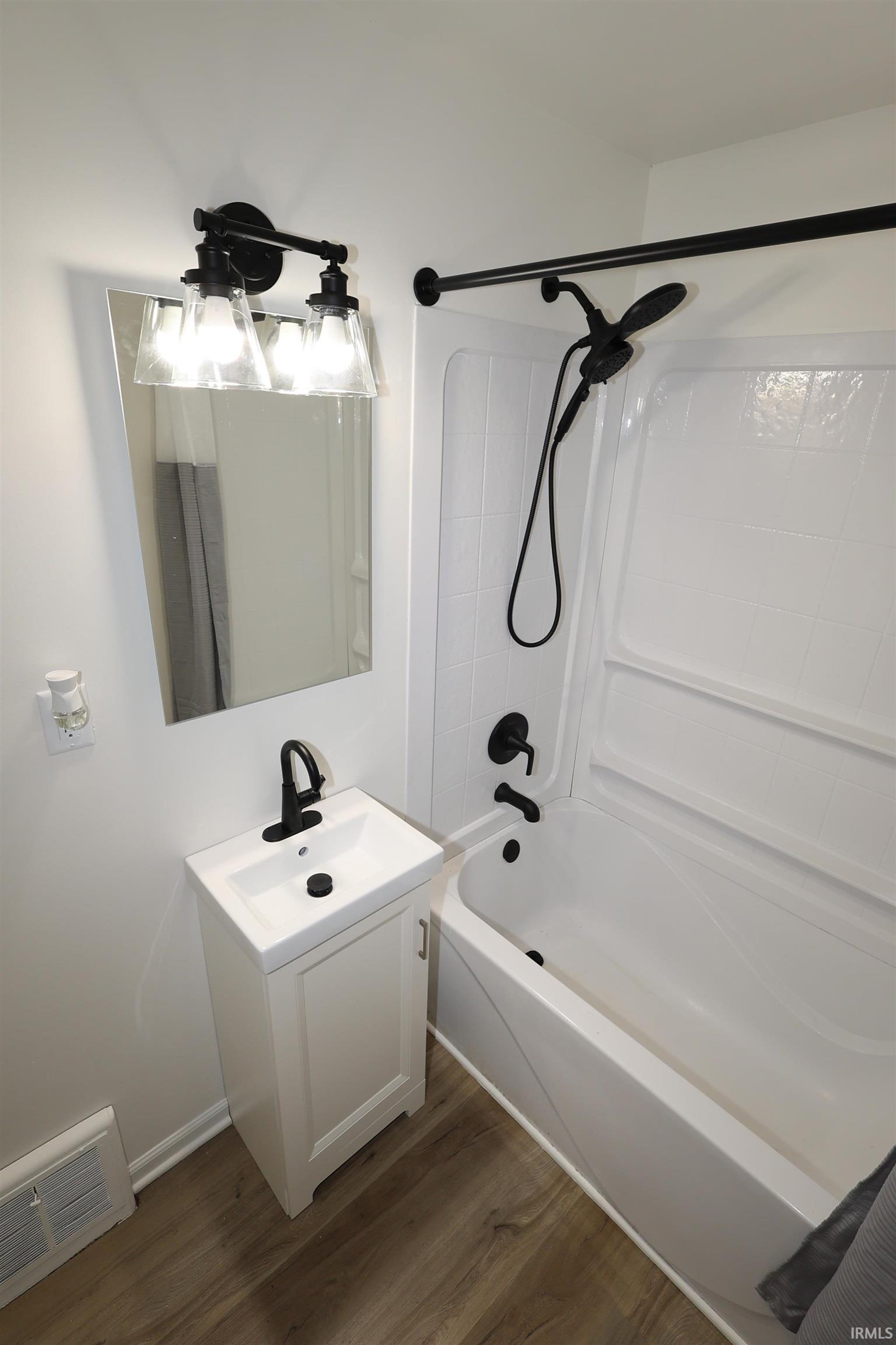 Bathroom featuring a white vanity with integrated sink, matte black faucet, and coordinating matte black lighting fixture