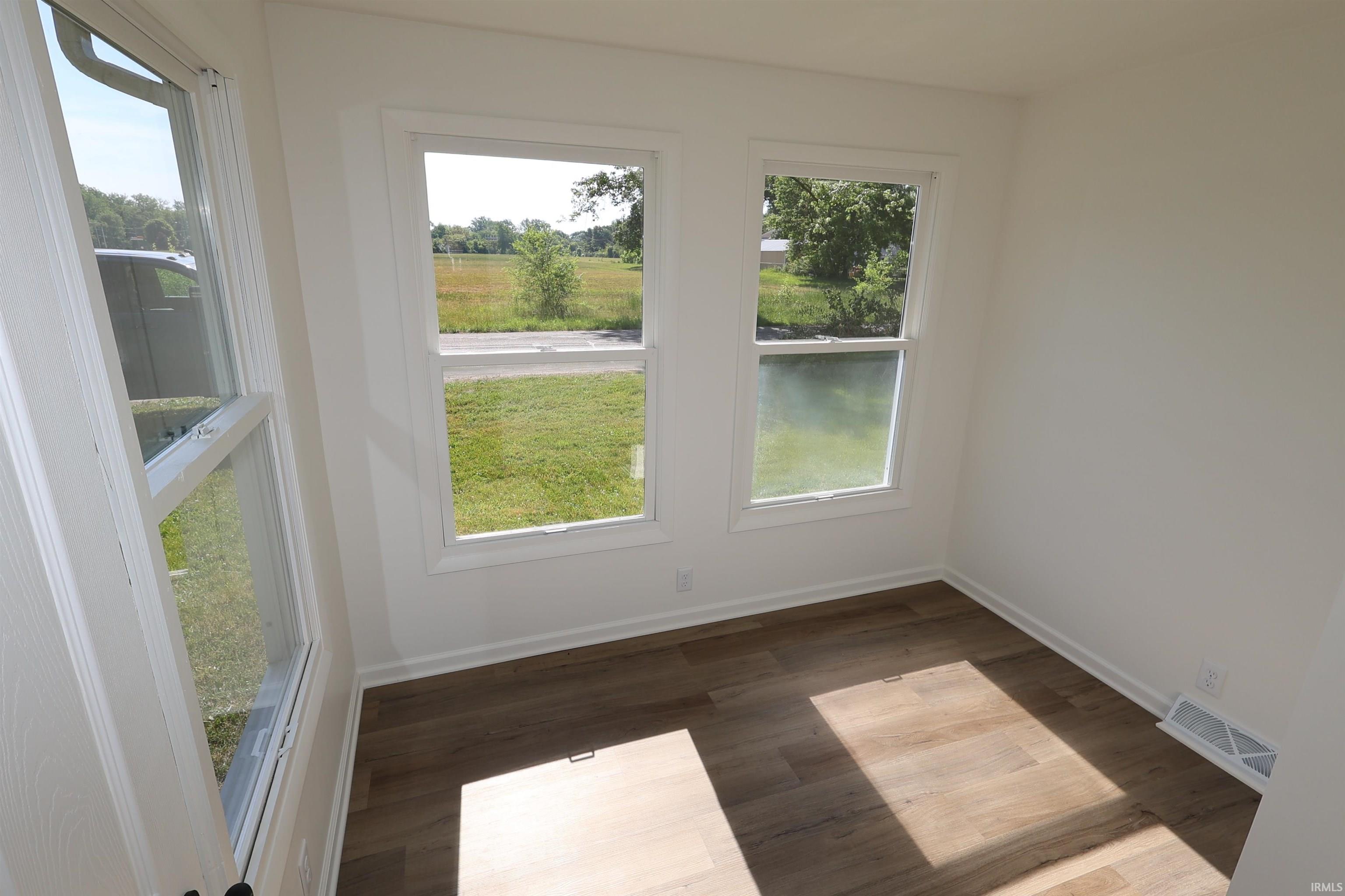 Room featuring wood-finish flooring, white baseboards, and bright white walls