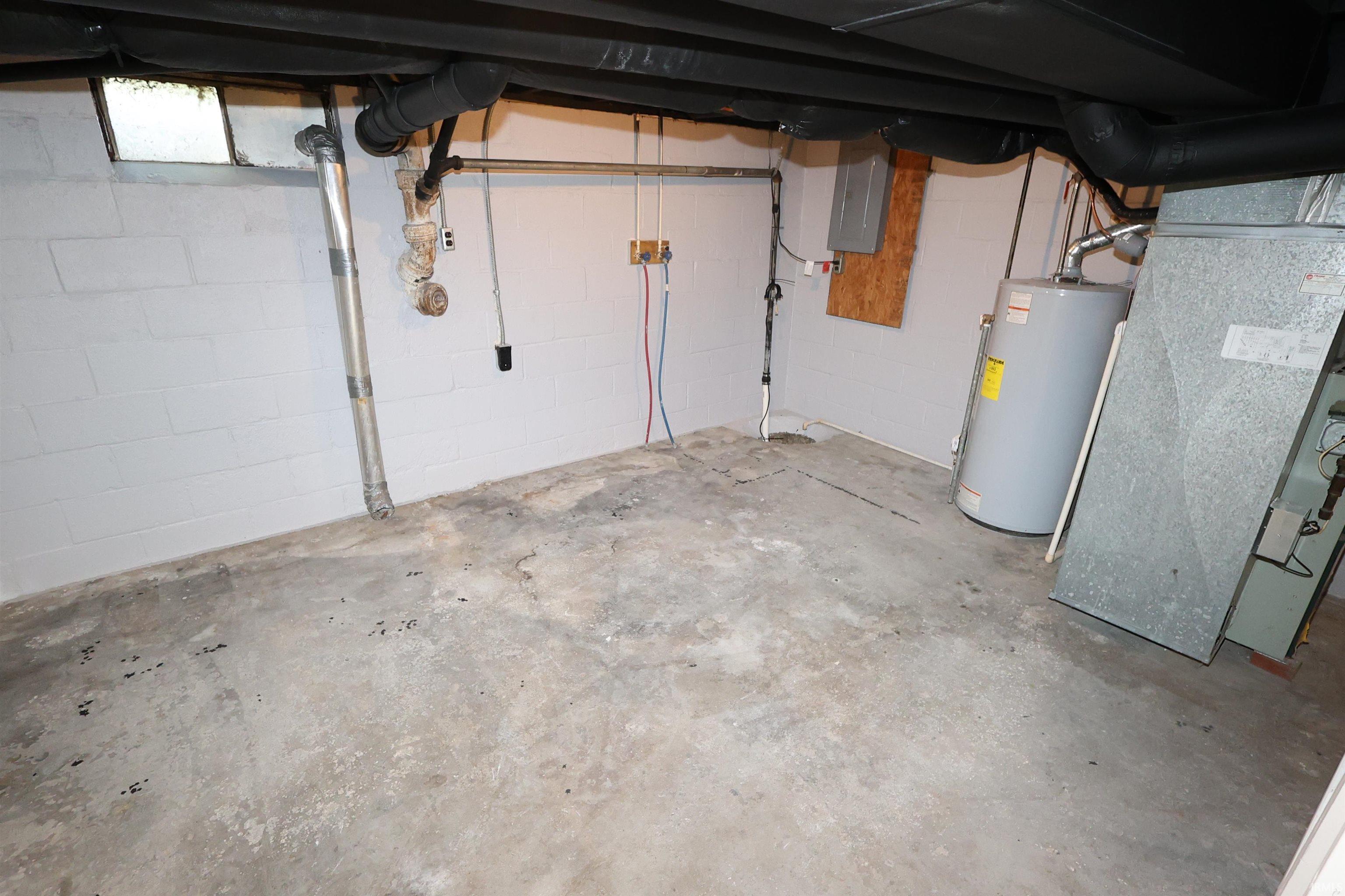 Basement utility area featuring a water heater, exposed overhead ductwork, and concrete block walls