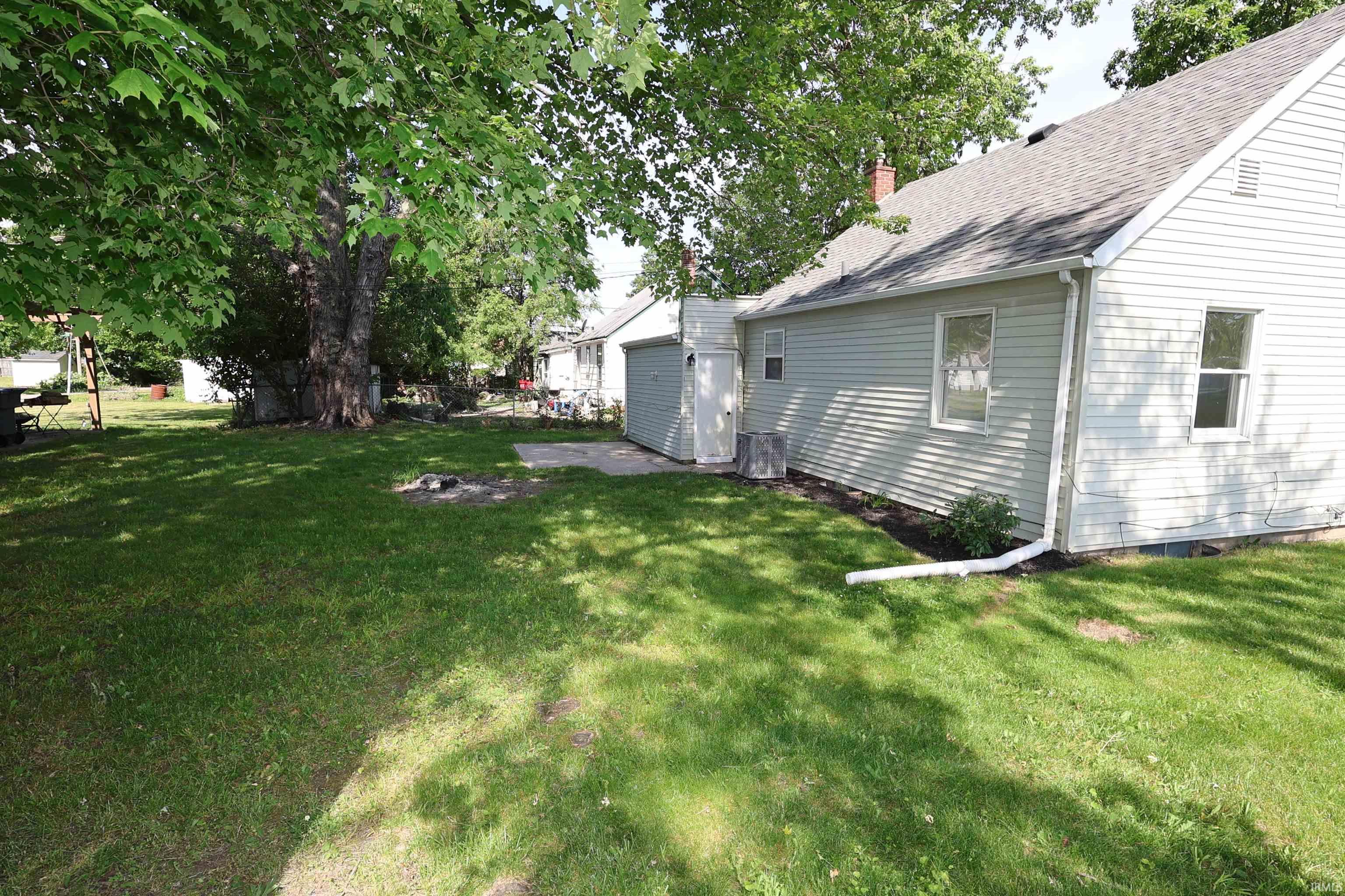 Spacious rear yard with a manicured lawn and mature shade trees