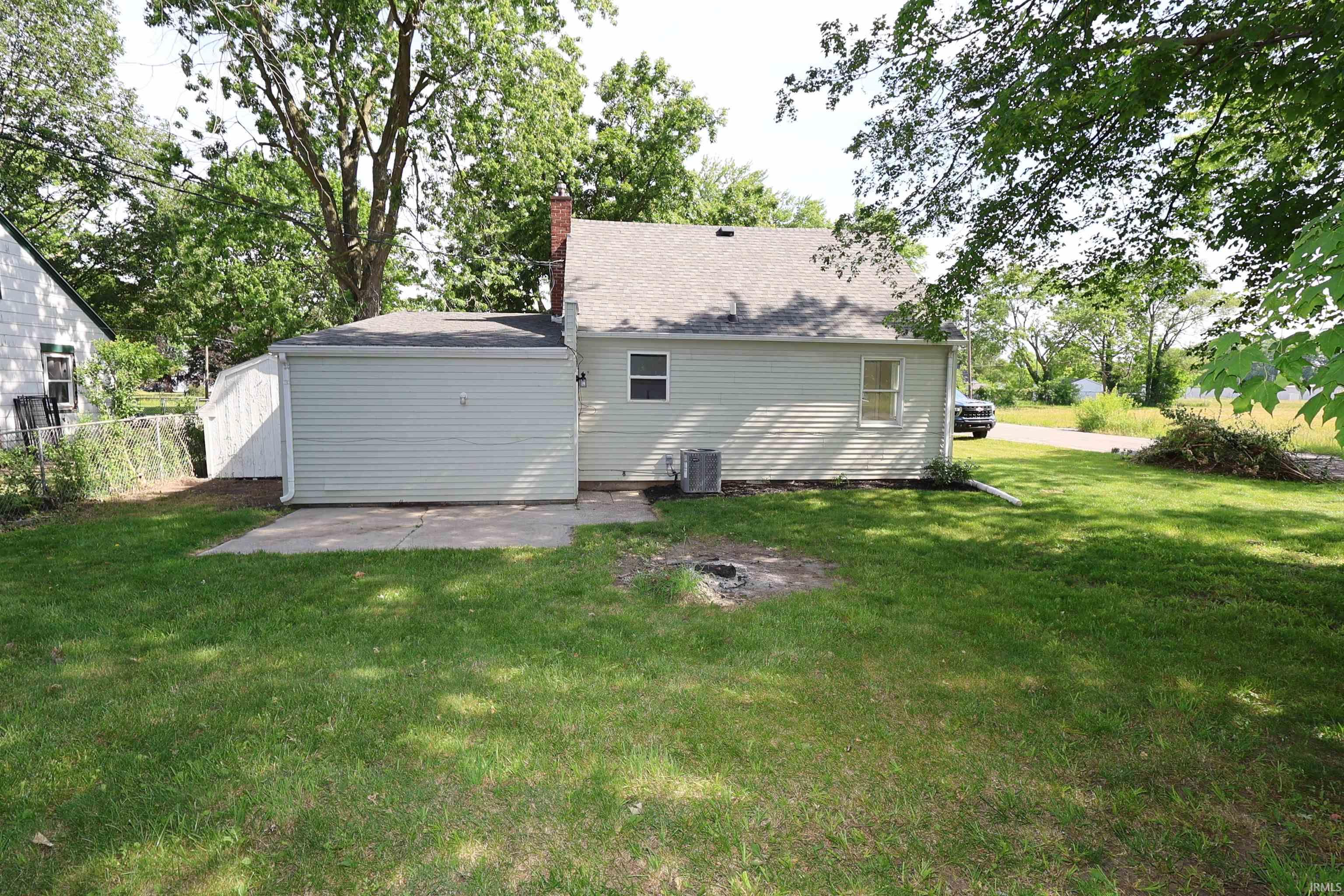 Expansive rear yard featuring green lawn, mature trees, and a detached garage with an attached shed