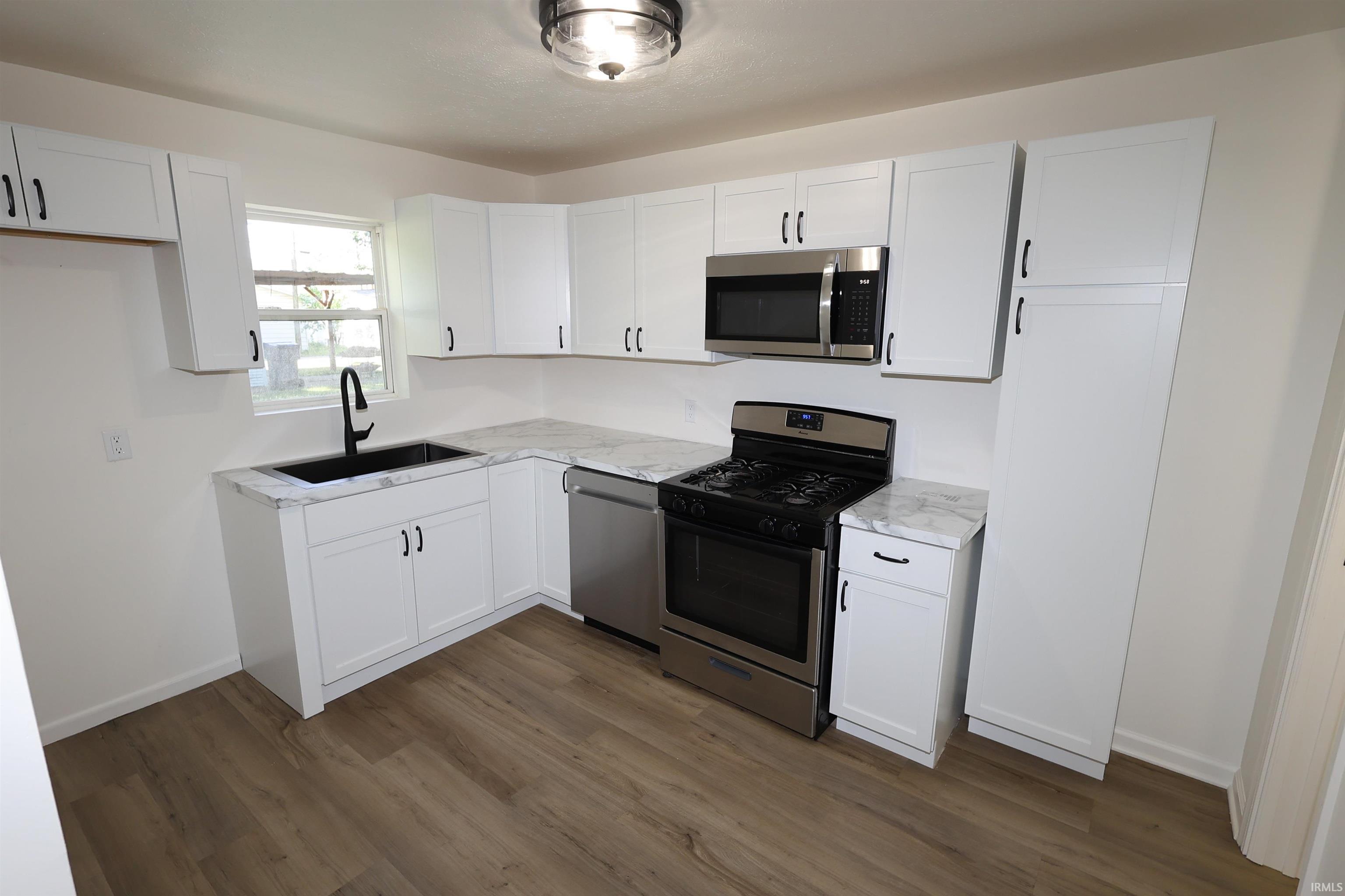 Contemporary kitchen featuring white cabinetry, stone-finish countertops, and stainless steel appliances