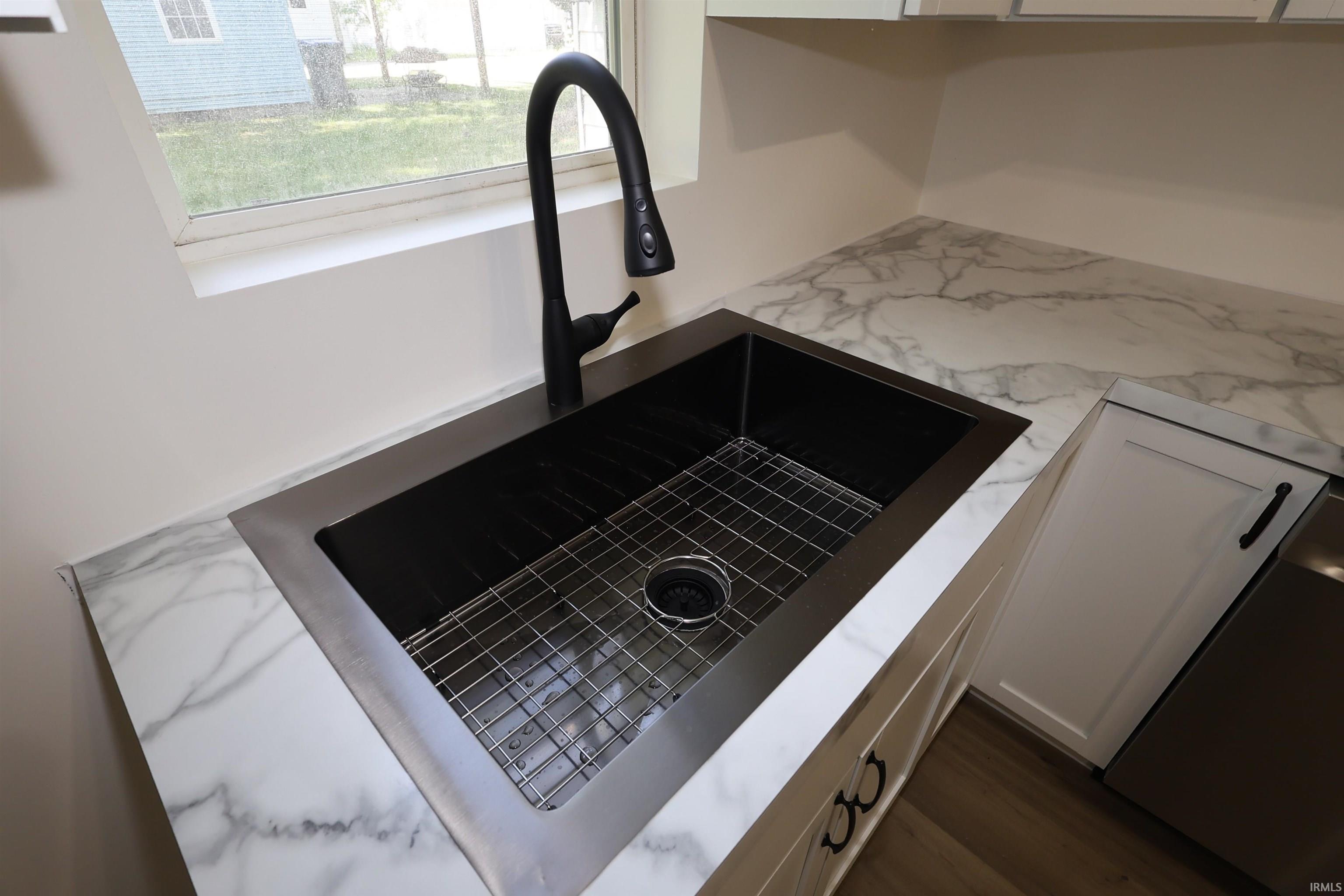Modern kitchen sink with a matte black high-arc faucet, undermount black sink, and stainless steel grid