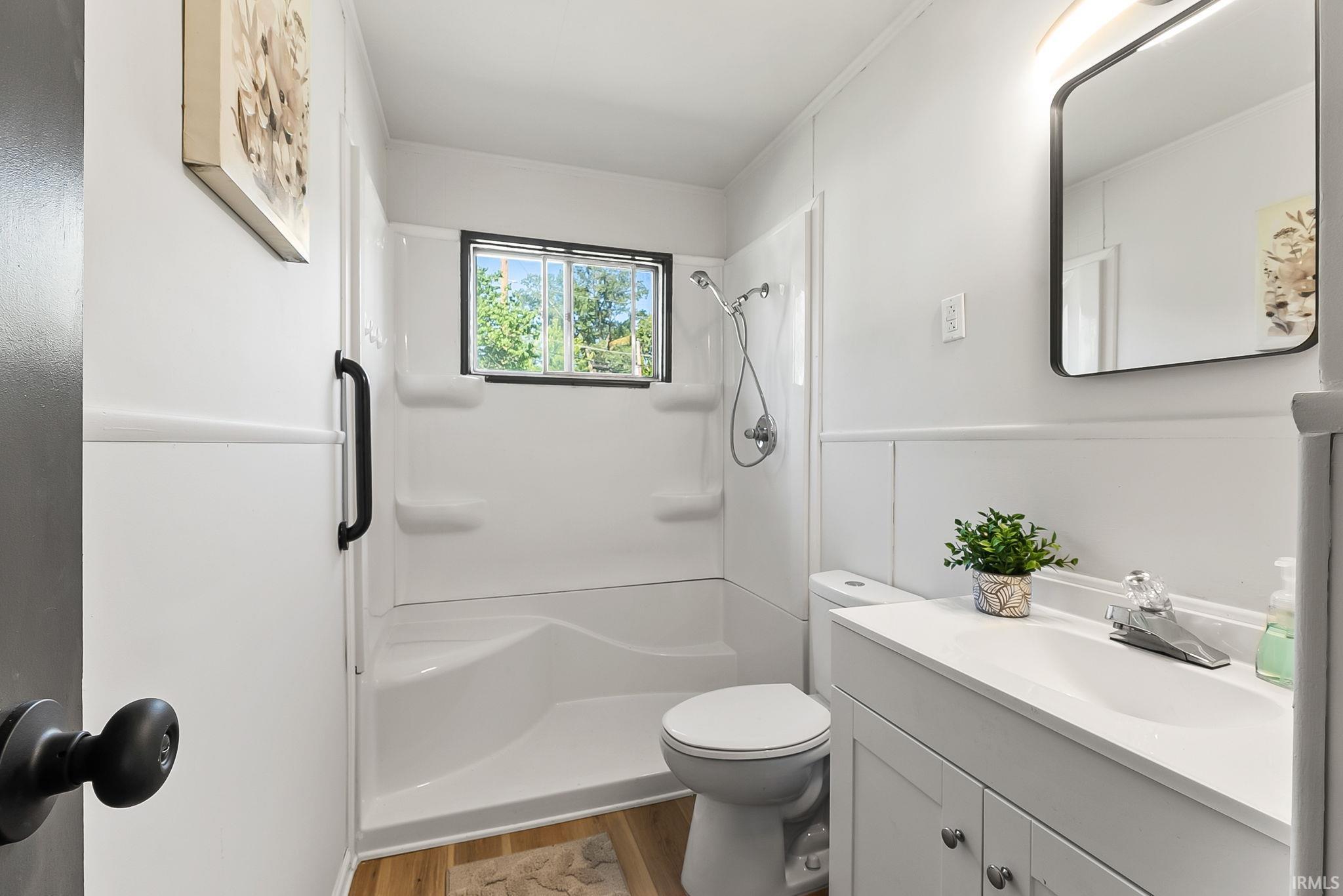 Bathroom featuring a white vanity with integrated sink, chrome faucet, and rectangular mirror with integrated lighting
