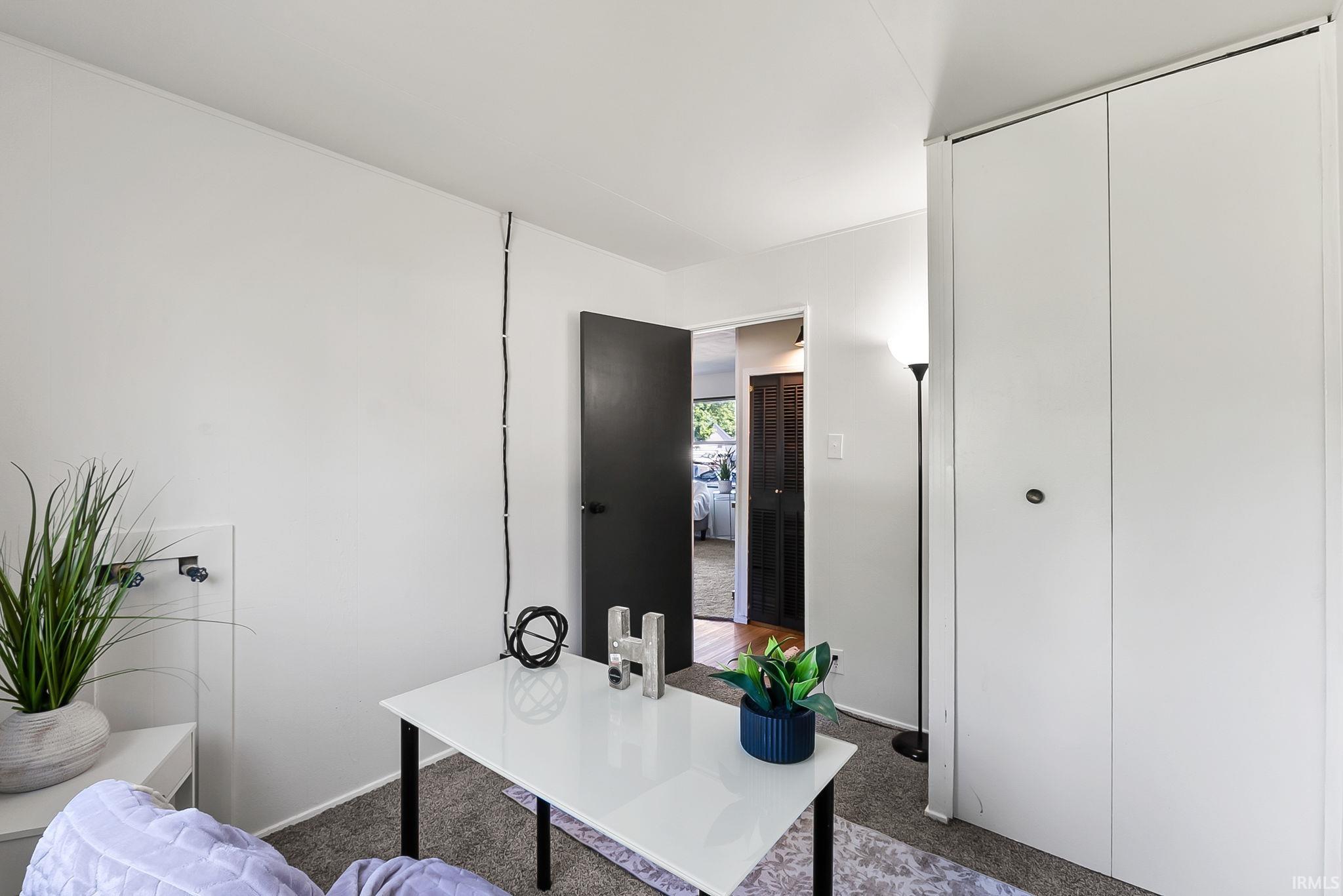 White bi-fold closet doors with black hardware, complementing the light gray carpet flooring