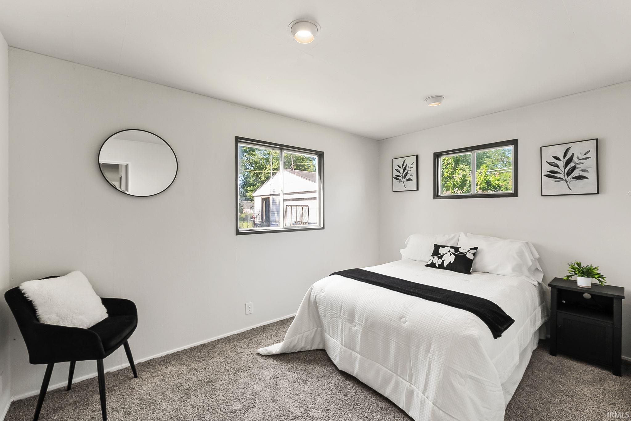 Bedroom featuring light gray walls, gray carpet flooring, black-framed windows, and recessed ceiling lighting