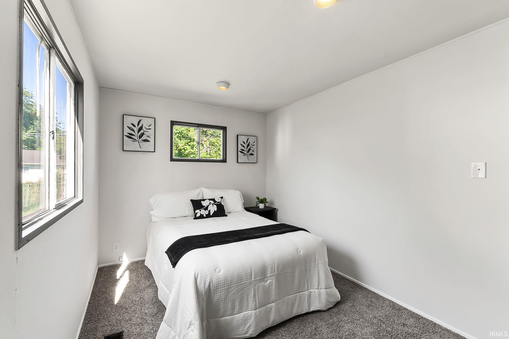 Bedroom featuring neutral-toned walls, gray carpeting, and dual windows