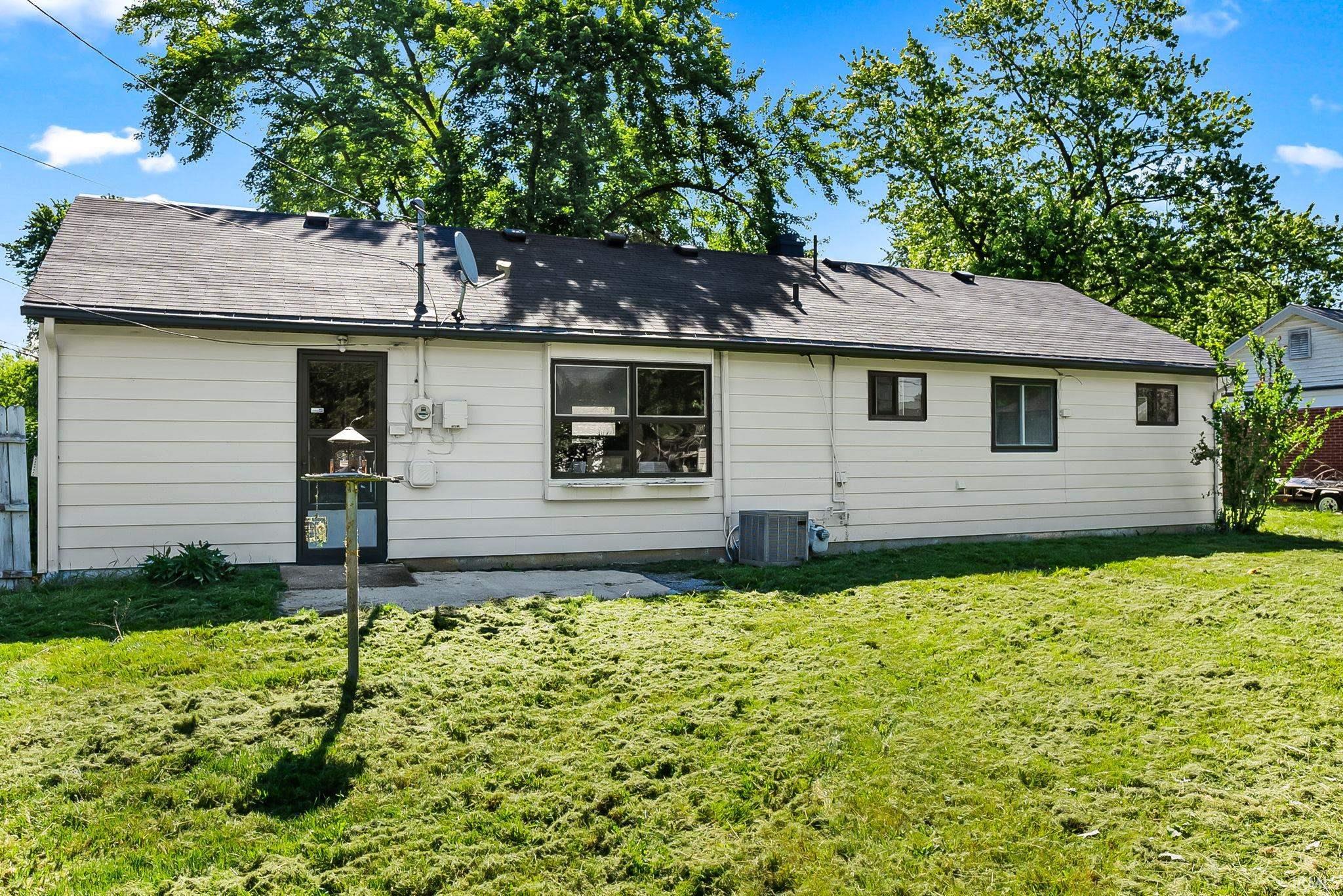 Rear exterior featuring white siding and a dark shingle roof