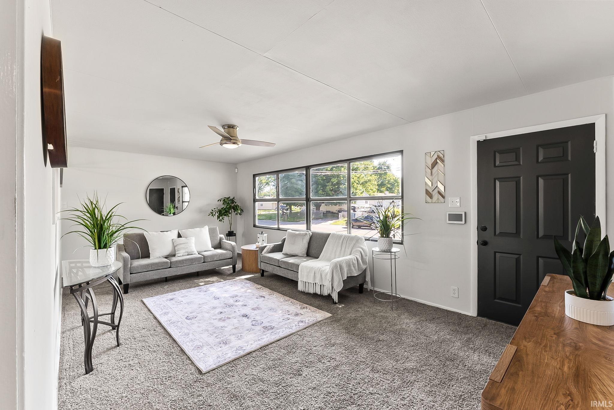 Inviting living area featuring light gray walls, a ceiling fan with integrated lighting, and multiple windows providing natural illumination