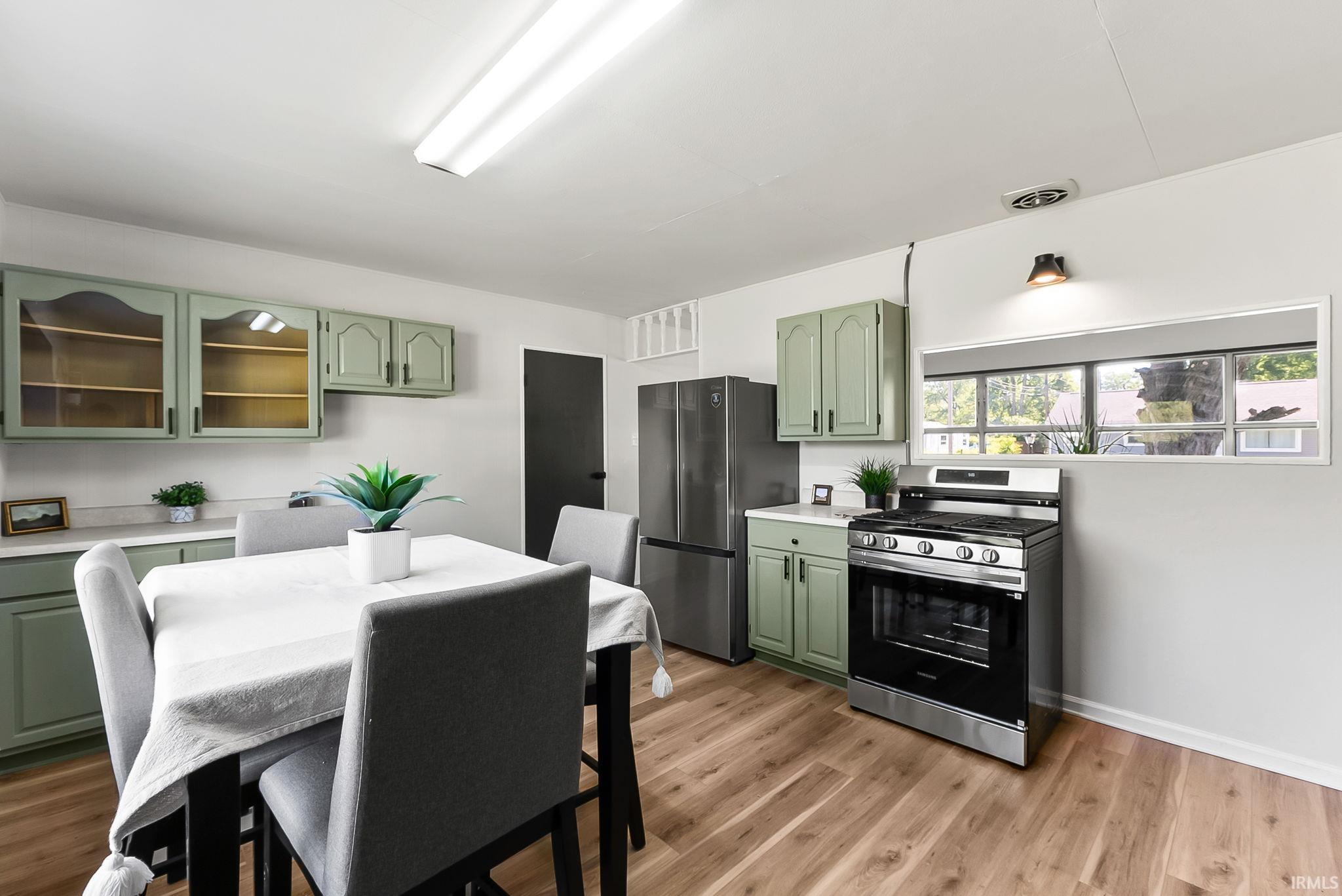 Kitchen space featuring wood-finish flooring and sage green cabinetry