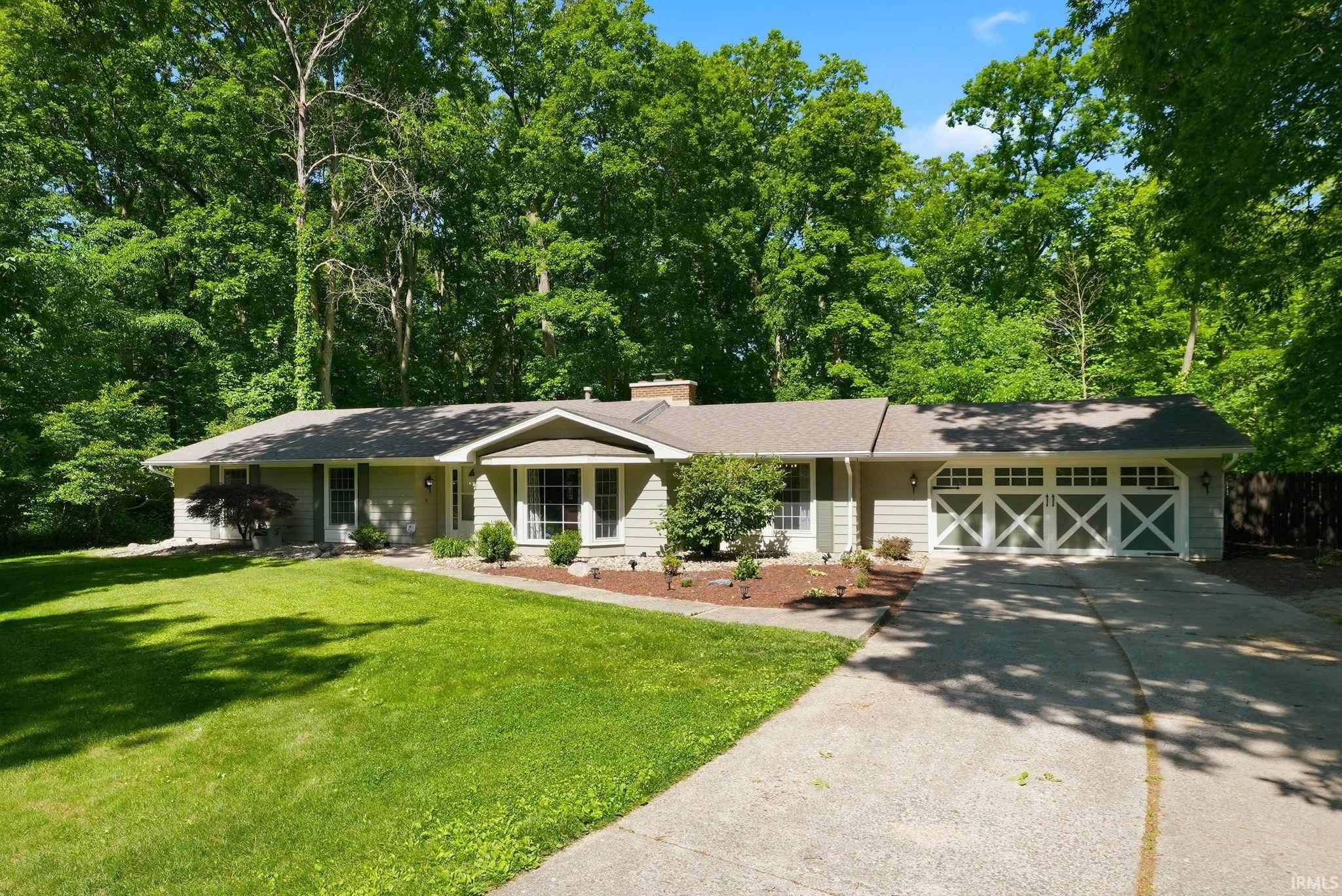 Ranch-style residence featuring light-colored siding and a two-car garage with decorative crossbuck doors